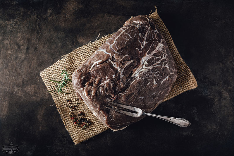 Eingelegter Sauerbraten mit Zwiebeln und Gewürzen – Traditionelles deutsches Rindfleischgericht Nahaufnahme eines rohen, eingelegten Sauerbraten-Stücks mit sichtbaren Pfefferkörnern, Zwiebelringen und Lorbeerblättern in einer dunklen Marinade – traditionelles deutsches Schmorgericht, perfekt vorbereitet zum Kochen.