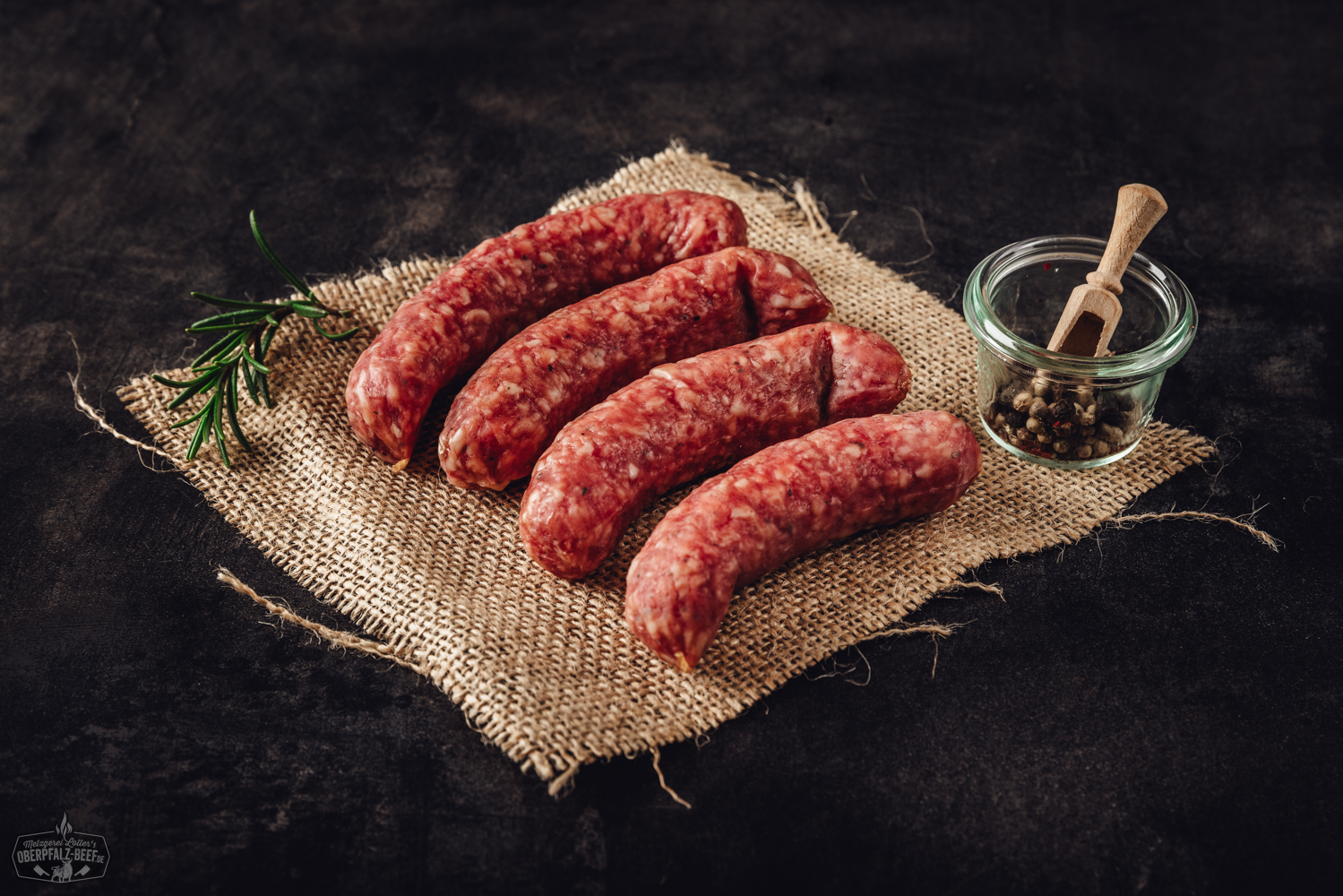 Mediterranos Grillplatte mit Rind, Gemüse und Rosmarin auf heißem Stein – Oberpfalz Beef Spezialität Weihnachtlich verpackte Salami in rotem Nikolausmantel mit weißem Bart und Mütze, stehend vor rustikalem Holz-Hintergrund, daneben Tannenzweige und Weihnachtsdekoration – festliche Wurst als Geschenkidee zu Weihnachten.