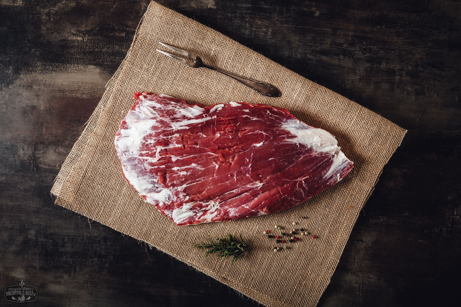 Flank Steak Wet Aged vom Oberpfalz Rind auf Holzbrett – Premium Rindfleisch Qualität Flank Steak vom Oberpfalz-Rind, wet-aged gereift, roh und saftig-marmoriert, auf dunklem Untergrund angerichtet mit dezenten Kräuterdetails – hochwertiges regionales Rindfleisch für Grill und Küche.