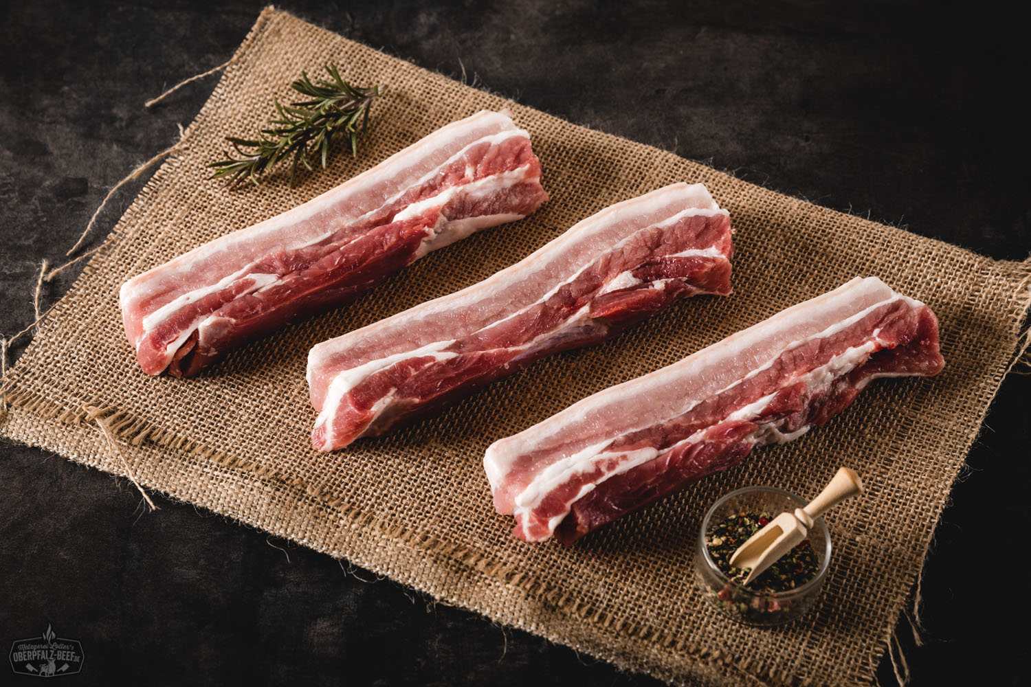 Rohes Bauchsteak vom Oberpfälzer Landschwein naturbelassen auf dunklem Untergrund, deutlich sichtbare Marmorierung und frische Fleischstruktur, als hochwertige Fleischspezialität für Grill oder Pfanne.