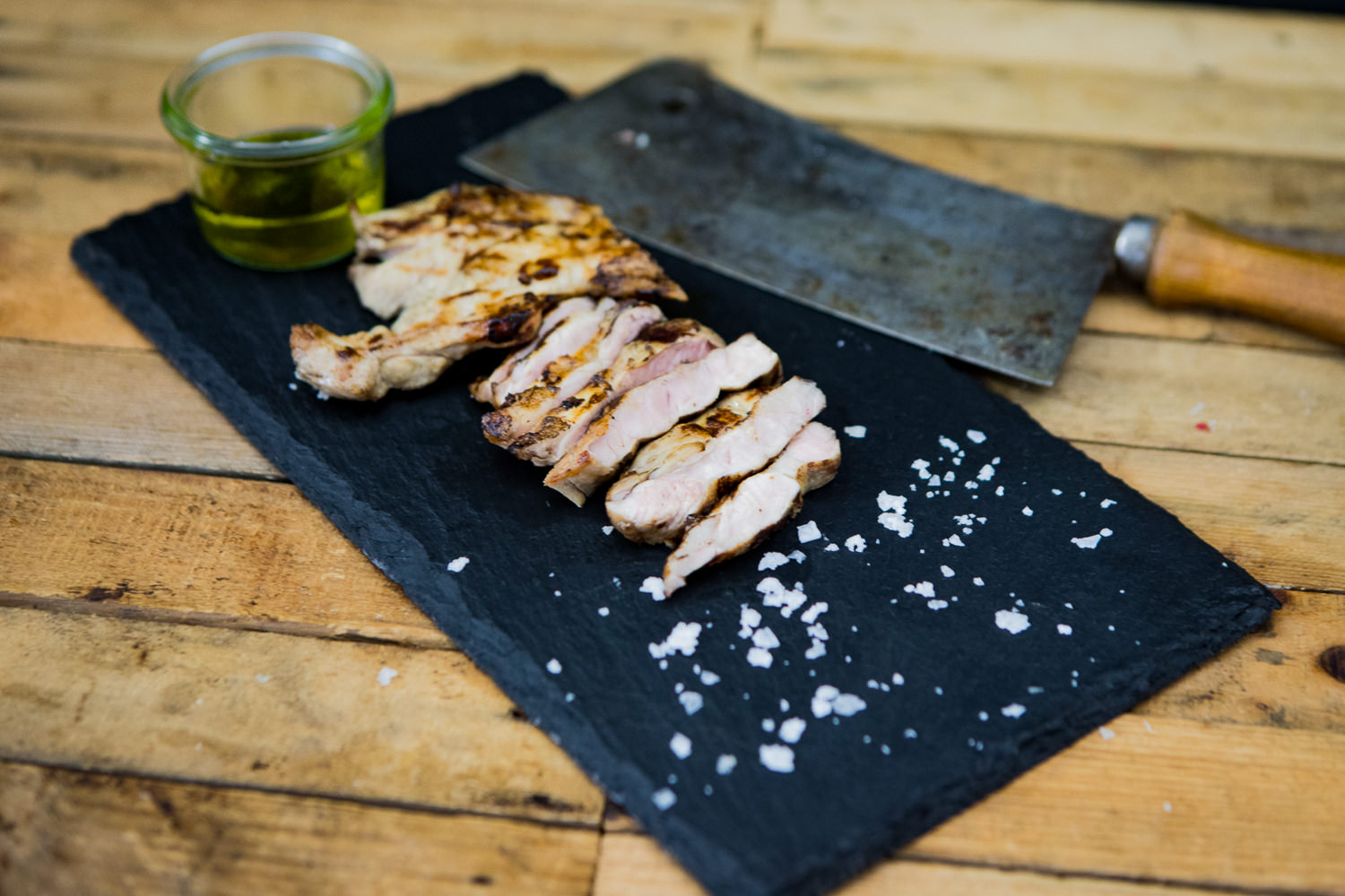 Kachelfleisch vom Oberpfälzer Landschwein frisch und regional kaufen Frisches Kachelfleisch vom Oberpfälzer Landschwein, roh und mager, auf naturbelassenem Holzbrett angerichtet, garniert mit Rosmarinzweig und Gewürzen – hochwertige Schweinefleisch-Zuschnitte ideal zum Grillen oder Braten.