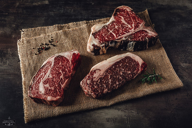 Ein elegantes Herrengedeck mit einem saftigen Oberpfalz Beef Steak, einem Glas Rotwein und stilvollem Besteck in rustikalem Ambiente. Perfekt für Genießer und Liebhaber hochwertiger Fleischgerichte.