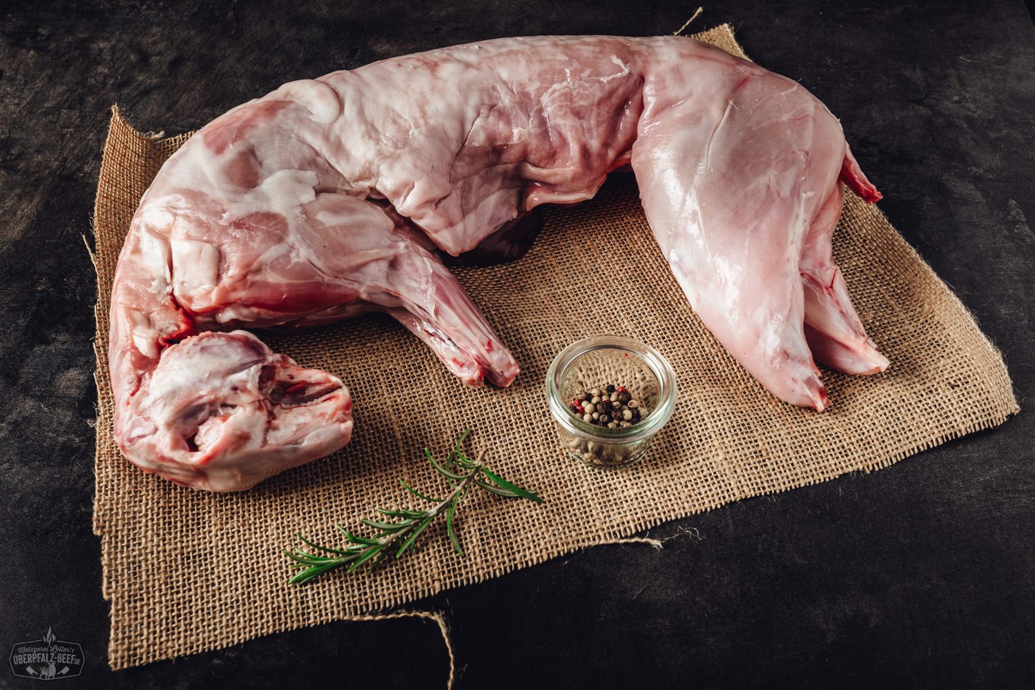 Kaninchenfleisch aus der Oberpfalz - Frisch und nachhaltig Bild zeigt ein frisches Kaninchenfleischstück, präsentiert auf einem hölzernen Schneidebrett, umgeben von Kräutern und Gewürzen. Perfekt für hochwertige Fleischliebhaber und traditionelle Kochrezepte aus der Oberpfalz.