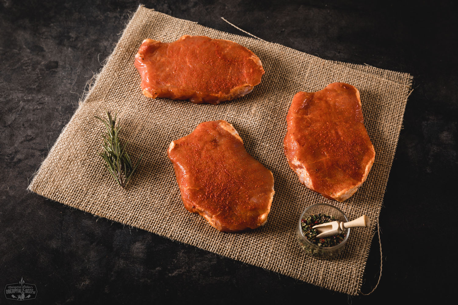 Gewürzte Rückensteaks vom Oberpfälzer Landschwein – Frisch & Regional Gewürzte Rückensteaks vom Oberpfälzer Landschwein roh auf schwarzem Grillrost angerichtet, mariniert mit Kräutern und Gewürzen, im rustikalen Stil präsentiert – hochwertige Fleischspezialität für Grillfans und Feinschmecker.