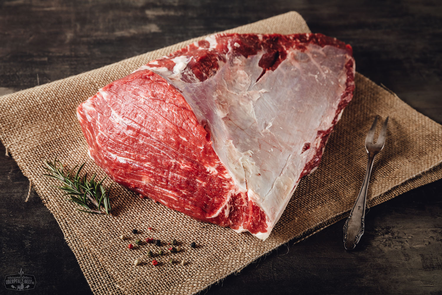 Rinderbraten aus der Schwanzrolle vom Oberpfalz-Rind aufgeschnitten auf Holzbrett, saftig und medium gegart, mit kräftiger Bräunung und sichtbarer Fleischstruktur, serviert mit Rosmarinzweig und Bratensaft – traditionelles Rindfleischgericht aus Bayern.