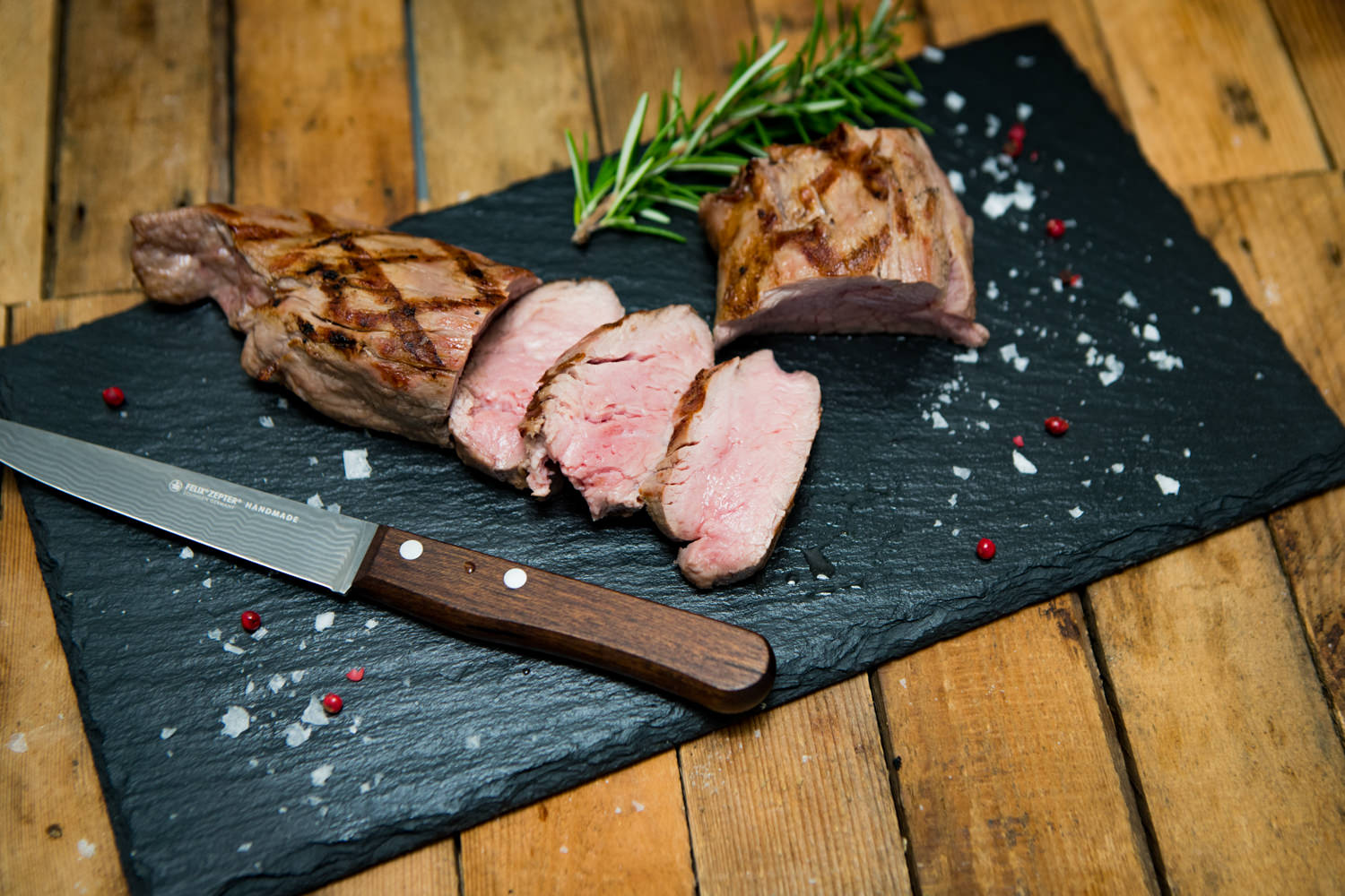 Filet vom Oberpfälzer Milchkalb – zartes Kalbfleisch in höchster Qualität Frisch gebratenes Filet vom Oberpfälzer Milchkalb auf einem Holzbrett angerichtet, serviert mit Rosmarinzweigen, grobem Meersalz und buntem Pfeffer – hochwertiges Kalbfleisch für Feinschmecker.