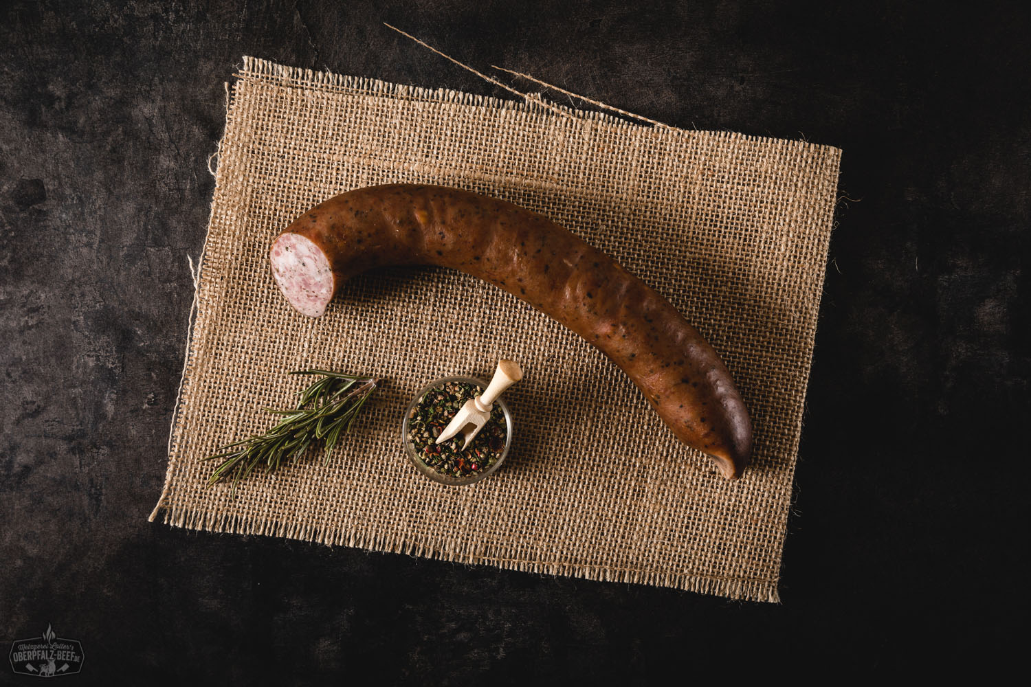 Hausmacher Stadtwurst im Glas – Traditionelle fränkische Wurstspezialität Hausmacher Stadtwurst in Aspik, serviert auf einem weißen Teller mit frischer Petersilie und Gewürzgurke, dazu frische Zwiebelringe – traditionelles bayerisches Wurstgericht, detailreich angerichtet auf hellgrauem Untergrund.