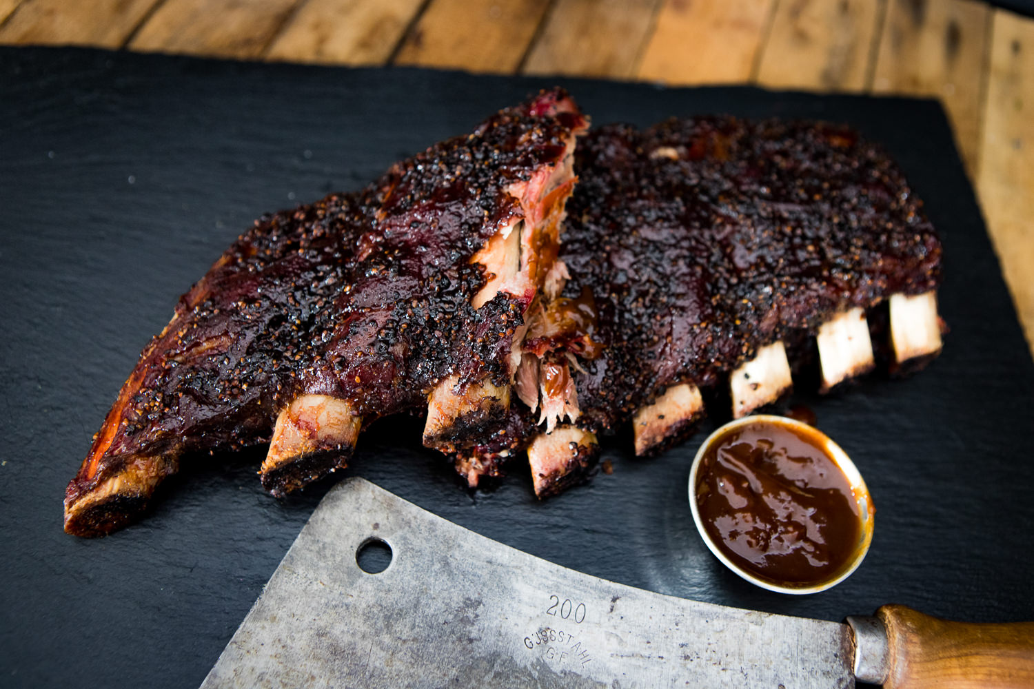 Dry Aged Back Ribs vom Oberpfalz-Rind – Premium Rindfleisch Qualität Dry Aged Back Ribs vom Oberpfalz-Rind, angerichtet auf dunklem Holzbrett mit grobem Salz, Pfefferkörnern und Rosmarinzweig – saftig gebräunte Rinderrippen mit sichtbarer Marmorierung in rustikaler Fleischpräsentation.