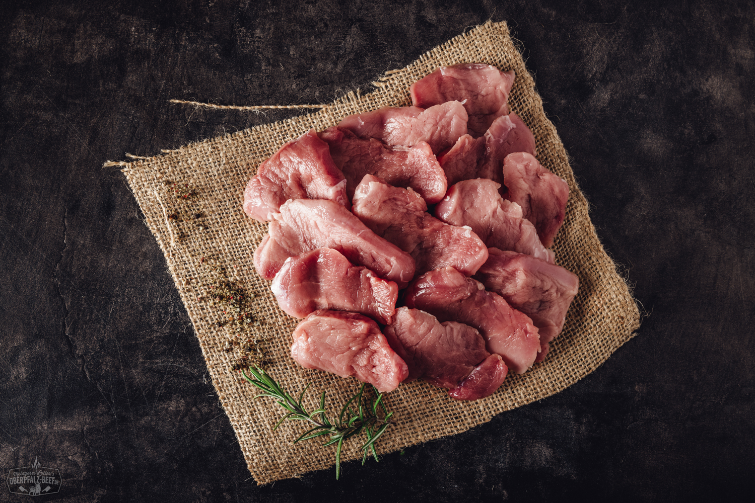 Handgeschnittenes Schweinefilet für Raclette – zartes Premiumfleisch aus der Oberpfalz Handgeschnittenes Schweinefilet für Raclette, roh und zart rosa, in feine Scheiben geschnitten und übereinandergelegt auf einem dunklen Untergrund, ideal für Raclette oder Grillgerichte.