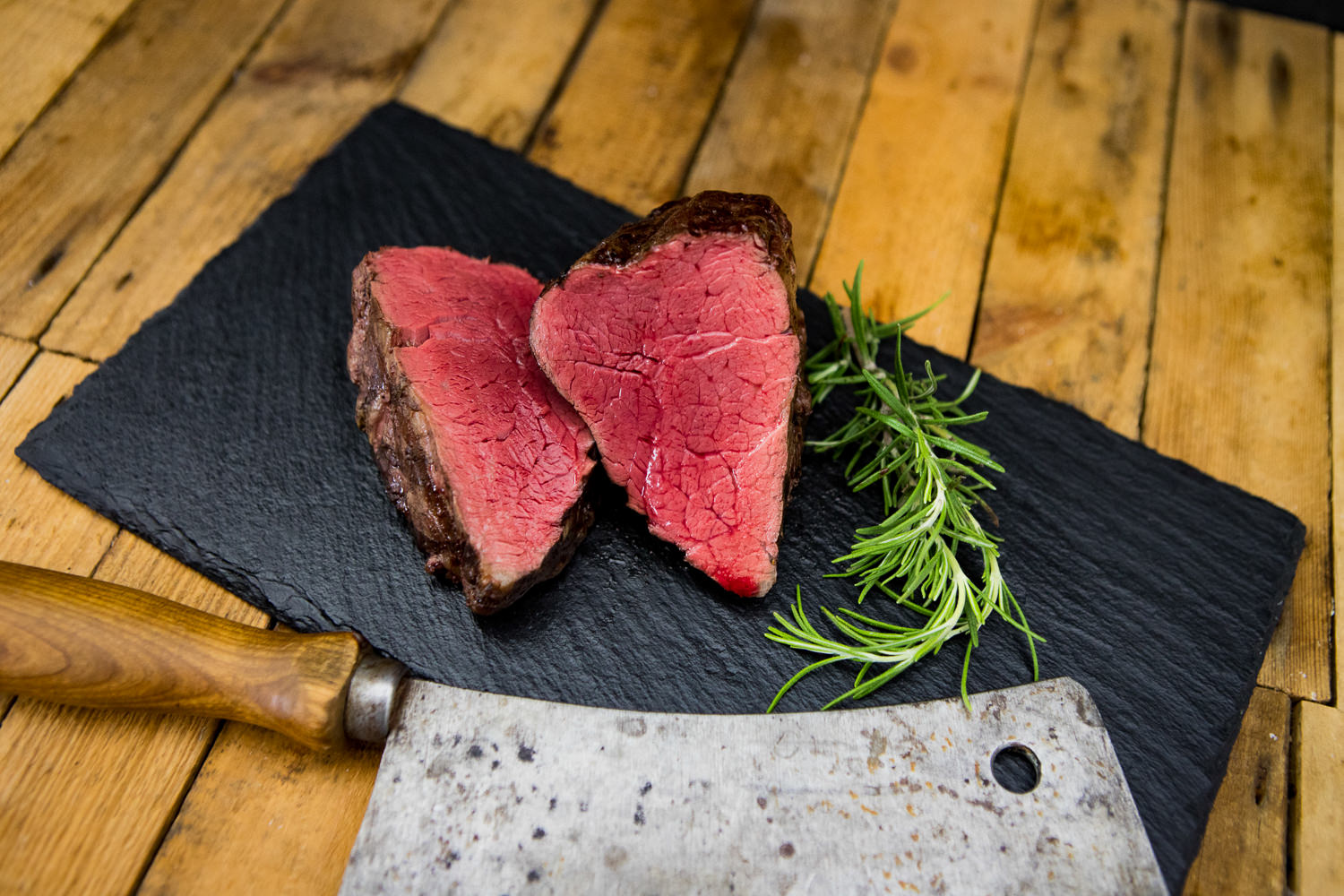 Filetspitzen vom Oberpfalz-Rind – Wet Aged Rindfleisch in Premium-Qualität Rohe Filetspitzen vom Oberpfalz-Rind auf schwarzem Schneidebrett, marmoriert und Wet Aged gereift, mit Rosmarinzweig und grobem Salz garniert – hochwertiges Rindfleisch für Steak oder Feinschmeckergerichte.
