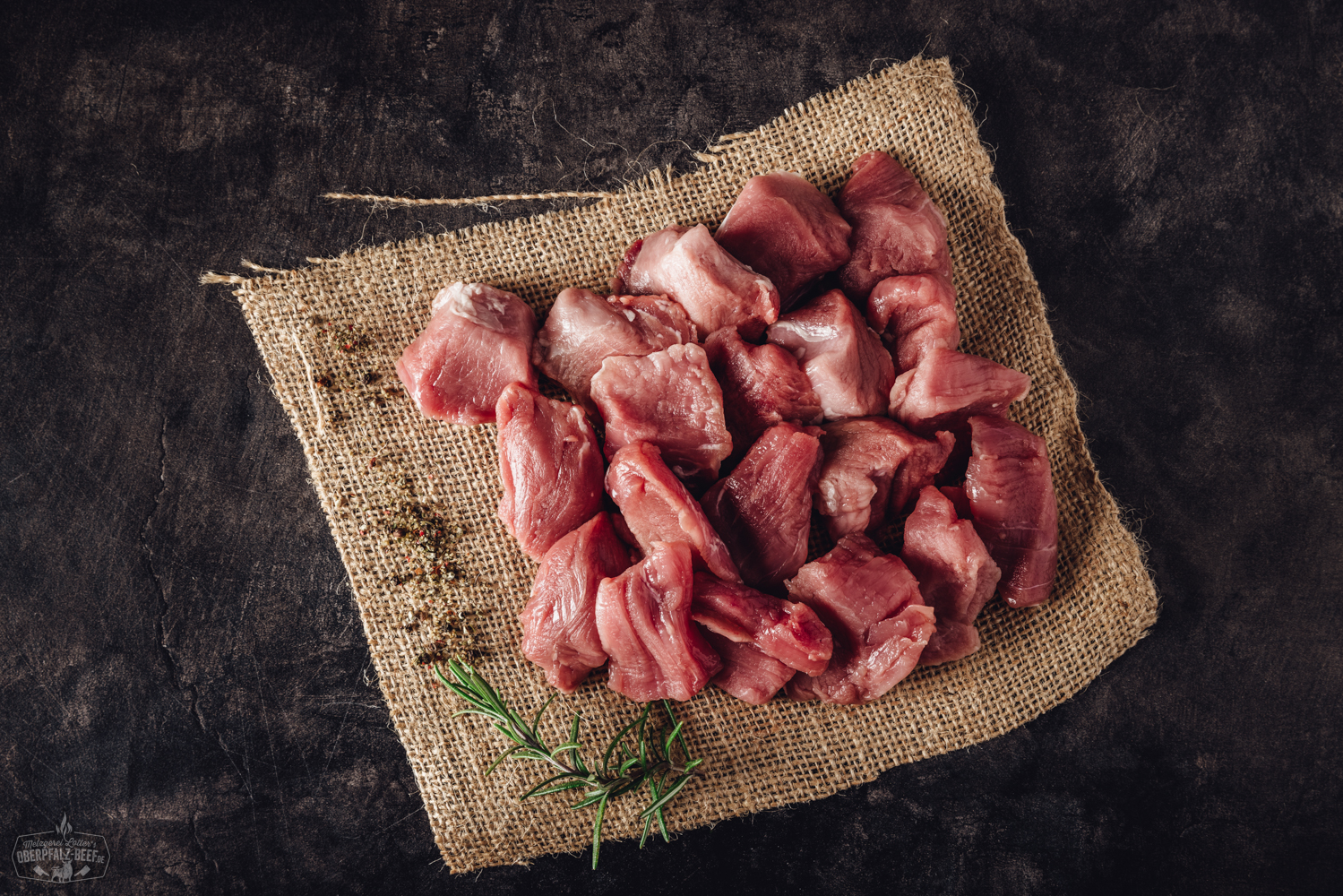 Handgeschnittenes Schweinefilet für Fondue – zartes Premiumfleisch aus der Oberpfalz Handgeschnittenes Schweinefilet für Fondue, roh und in feine Scheiben geschnitten, appetitlich auf einem dunklen Brett angerichtet, daneben frische Kräuter und Gewürze – hochwertiges Fondue-Fleisch aus der Oberpfalz.