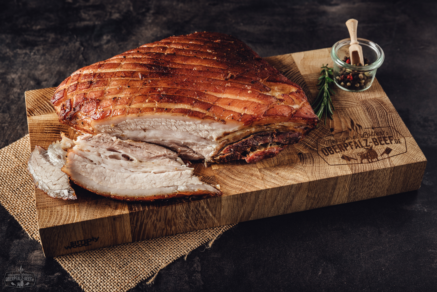 Sous-vide gegarter Krustenbraten vom Schweinebauch mit krosser Kruste auf Schneidebrett Ein köstlicher, sous vide vorgegarter Krustenbraten vom Schweinebauch mit knuspriger Kruste auf einem rustikalen Holzbrett präsentiert.