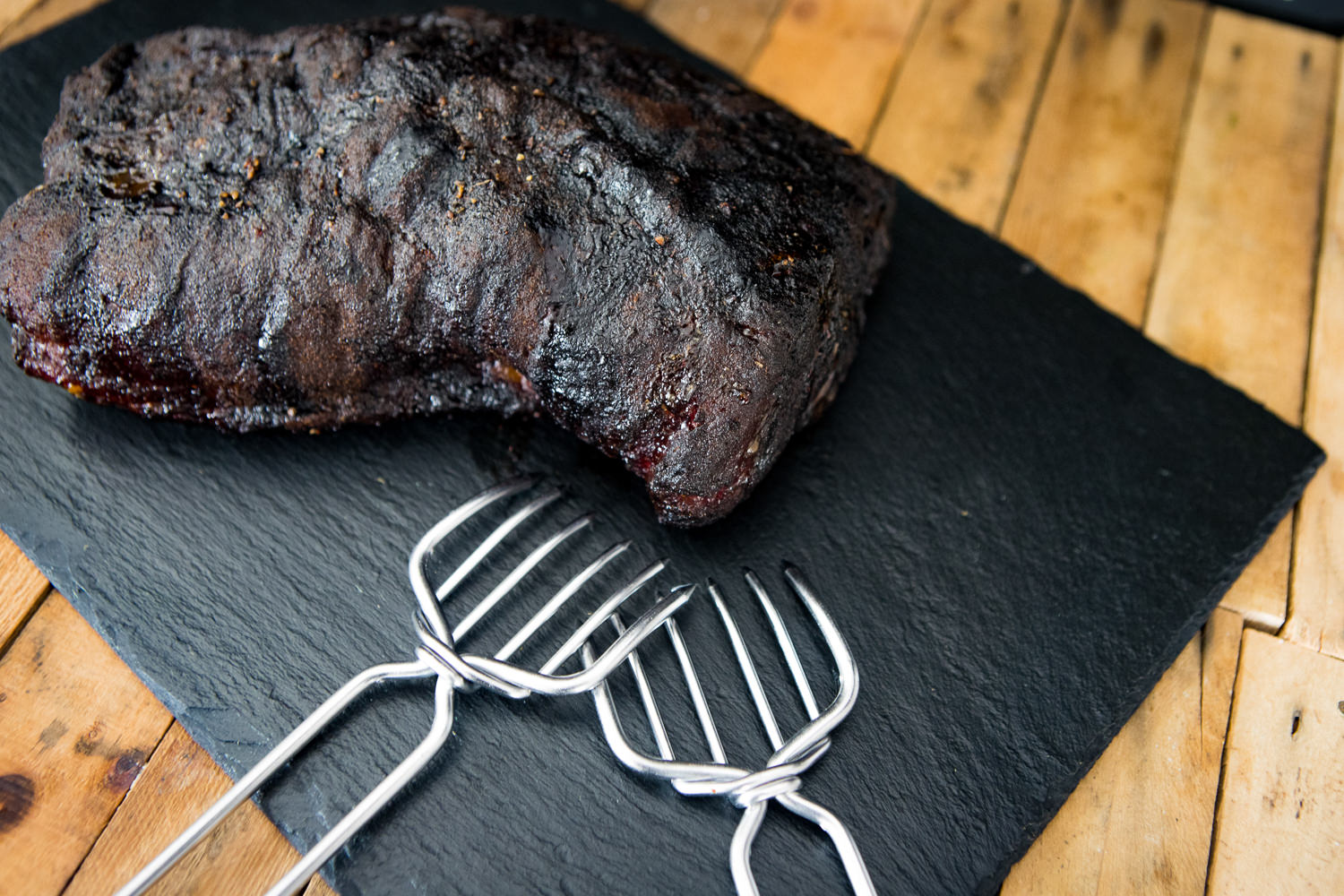 Pulled Pork Paket – Zartes BBQ-Fleisch aus der Oberpfalz kaufen Pulled Pork Paket von Oberpfalz Beef auf Holzuntergrund: Vakuumverpacktes, fertig gegartes Pulled Pork in aromatischer BBQ-Soße vor Grillbesteck und Gewürzen, ideal für Burger, Sandwiches oder BBQ-Gerichte.