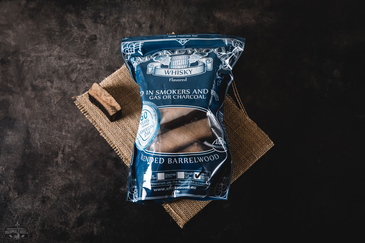 Smokewood Whisky Mini Blocks – Rauchholz für authentisches BBQ-Aroma Smokewood Whisky Mini Blocks in transparenter Verpackung auf weißem Hintergrund – kleine aromatisierte Holzstücke zum Räuchern von Fleisch oder Fisch beim BBQ, Produktetikett mit Markenlogo und Anwendungshinweisen sichtbar.