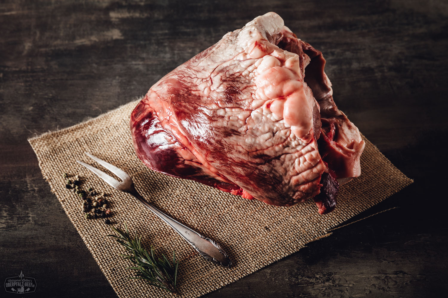 Herz vom Oberpfälzer Milchkalb – Frisches Kalbfleisch aus artgerechter Haltung Rohes Kalbsherz vom Oberpfälzer Milchkalb auf dunklem Untergrund, in Nahaufnahme präsentiert; das dunkle, glänzende Muskelfleisch ist frisch, sauber pariert und vegan-freundlich inszeniert für hochwertige Fleischvermarktung und regionale Spezialitäten.