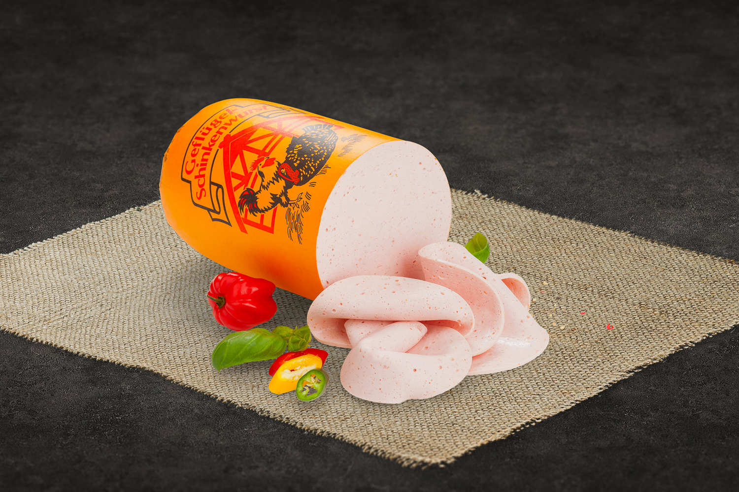 Geschnittener Puten-Bierschinken in dünnen Scheiben auf einem Holzbrett angerichtet, daneben ein Zweig Rosmarin und etwas grobes Salz – ideal als Brotbelag oder Aufschnitt für Feinschmecker.