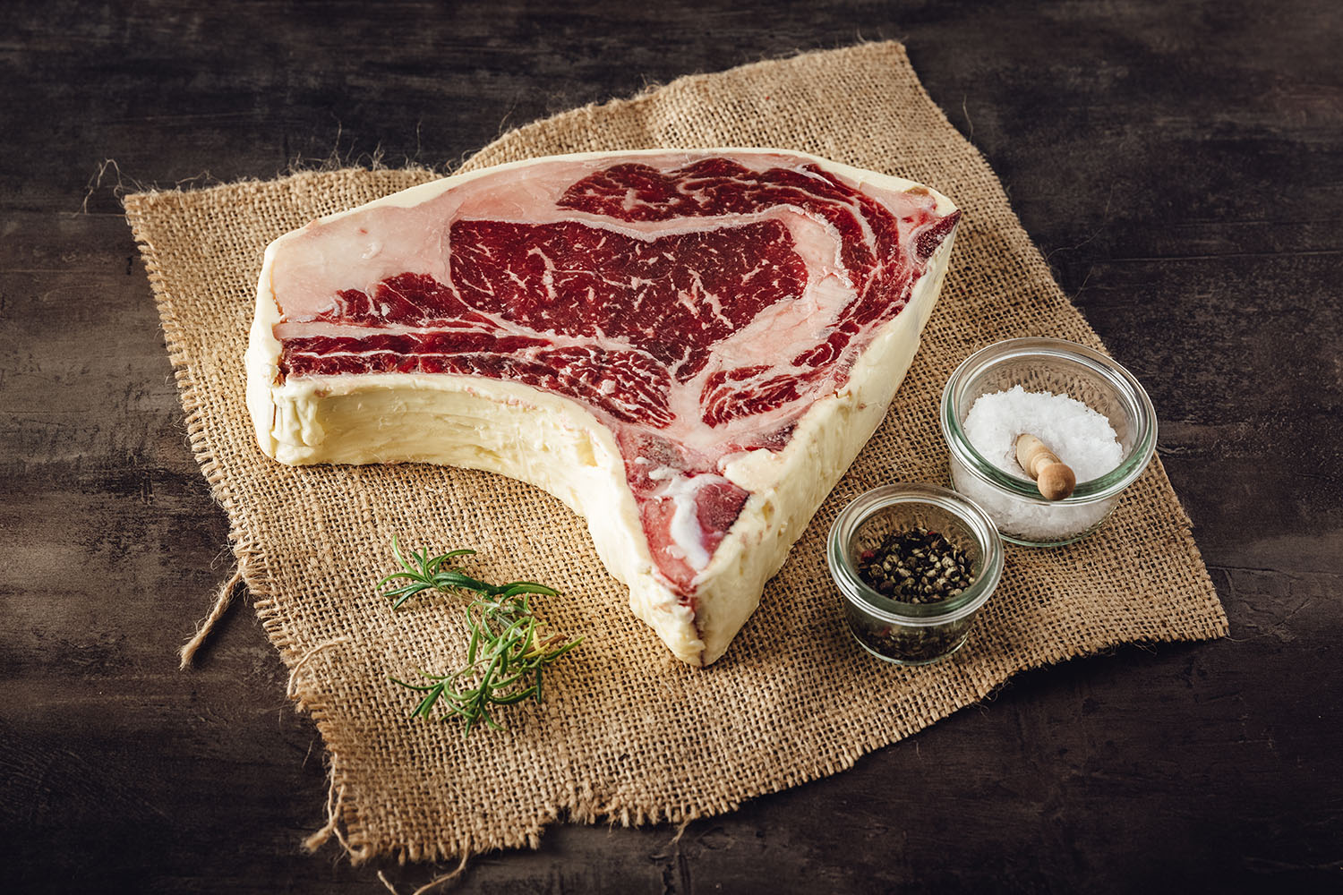 Rohes Bone-in-Ribeye-Steak vom Oberpfälzer Rind auf dunklem Untergrund, marmoriert und dry aged, mit sichtbarem Fettauge – hochwertiges Entrecôte für Grill oder Pfanne.