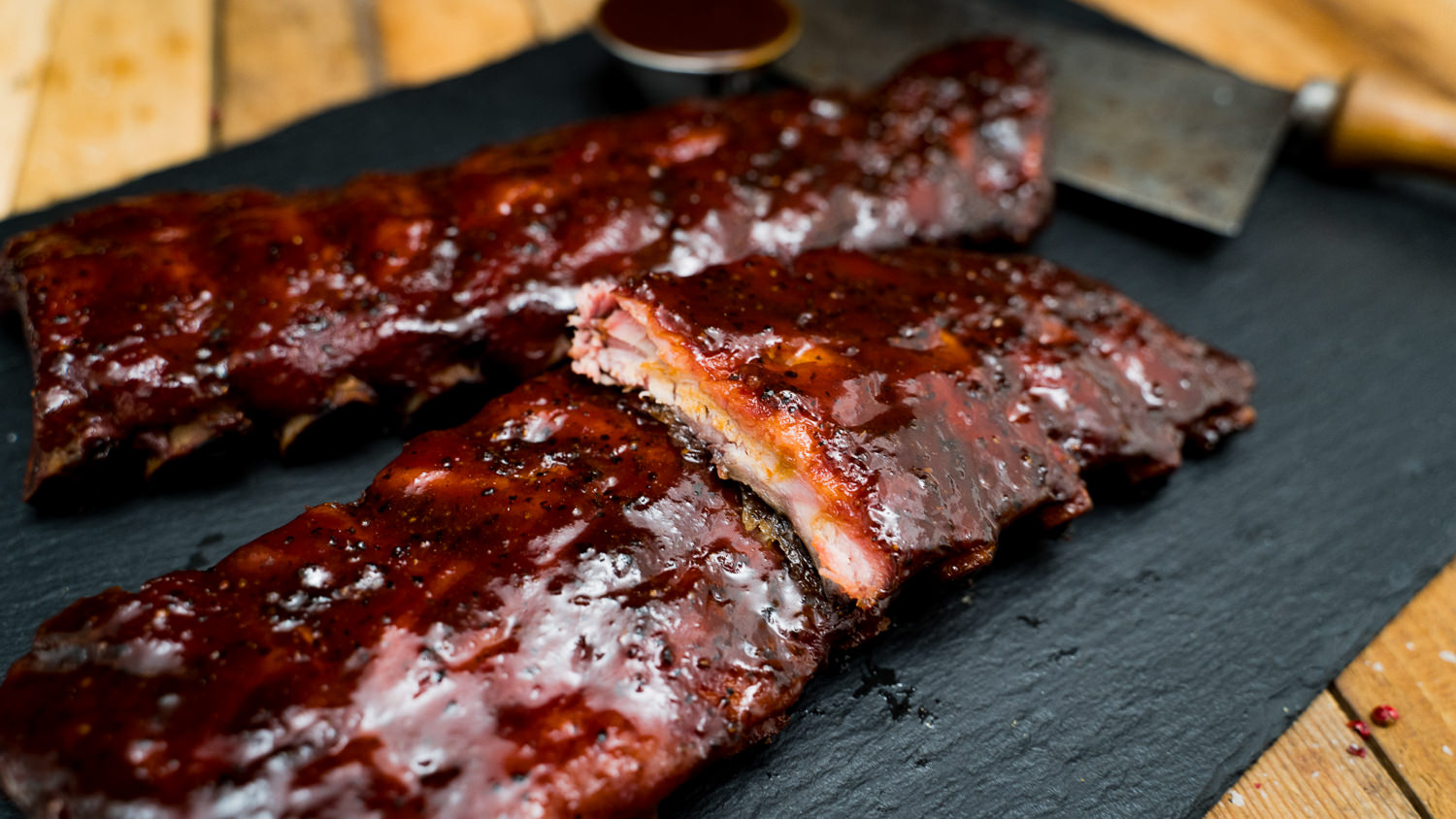 Extra Fleischige Babyback Ribs vom Grill – Zartes BBQ-Rippchen Genuss Frisch gegrillte Babyback Ribs mit knuspriger Kruste und intensiver Fleischstruktur auf Holzbrett angerichtet, glasiert mit Barbecue-Soße, daneben Gewürze und frische Kräuter – saftige Spareribs perfekt zum Grillen oder BBQ-Abend.