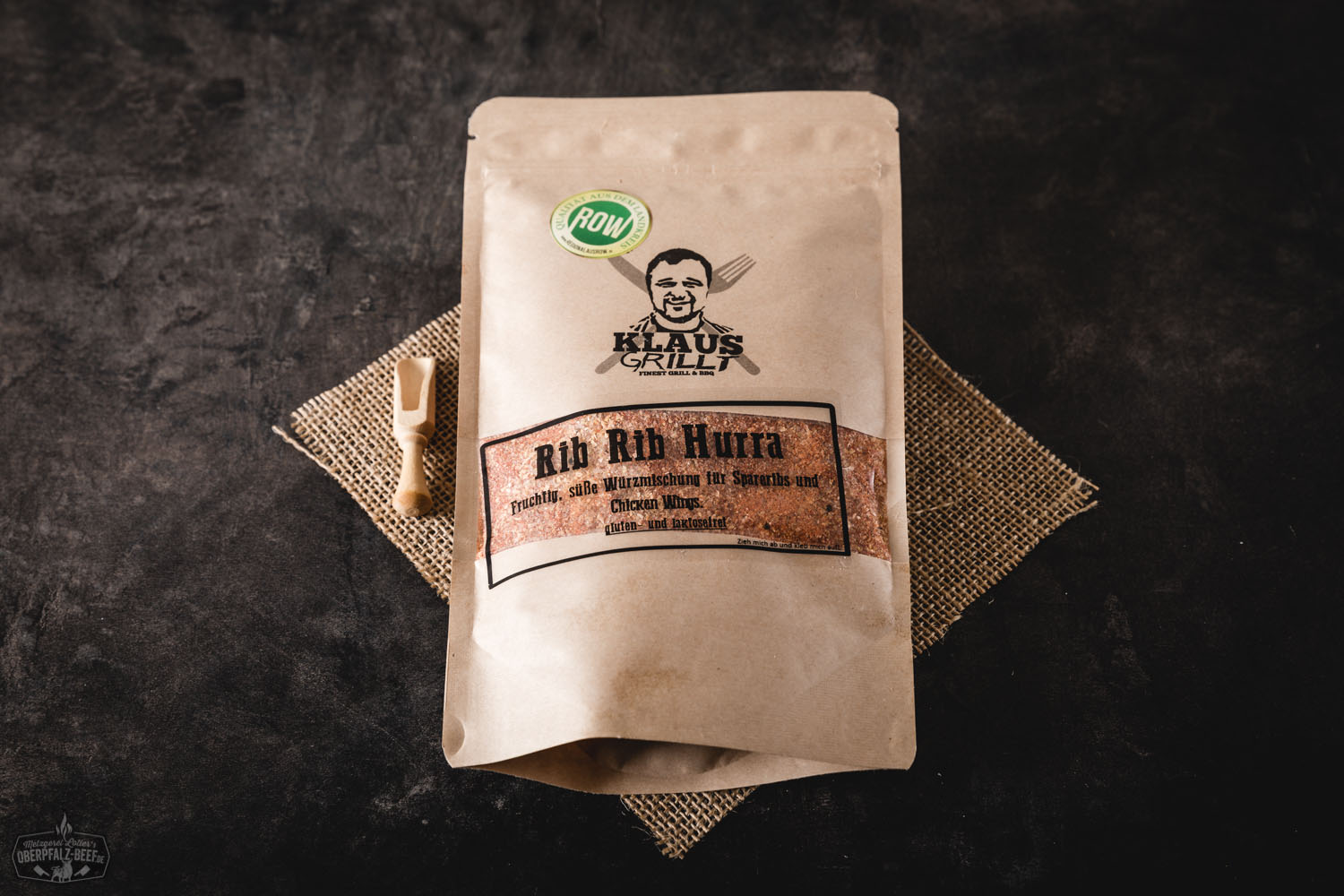 Mann grillt Rindfleischrippen über Holzkohlegrill im Freien; saftiges Beef mit dunkler Kruste wird mit Grillzange gewendet – rustikale Zubereitung von BBQ-Ribs bei Tageslicht.