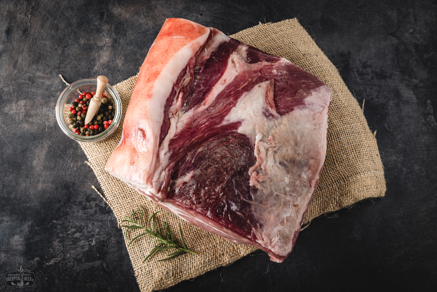 Entrecôte am Stück Dry Aged vom Oberpfälzer Landschwein – Premium Schweinefleisch kaufen Dry Aged Entrecôte vom Oberpfälzer Landschwein im Ganzen, roh, mit kräftiger Marmorierung, auf dunklem Untergrund präsentiert – hochwertiges Premium-Schweinefleisch für Steakliebhaber und Feinschmecker.