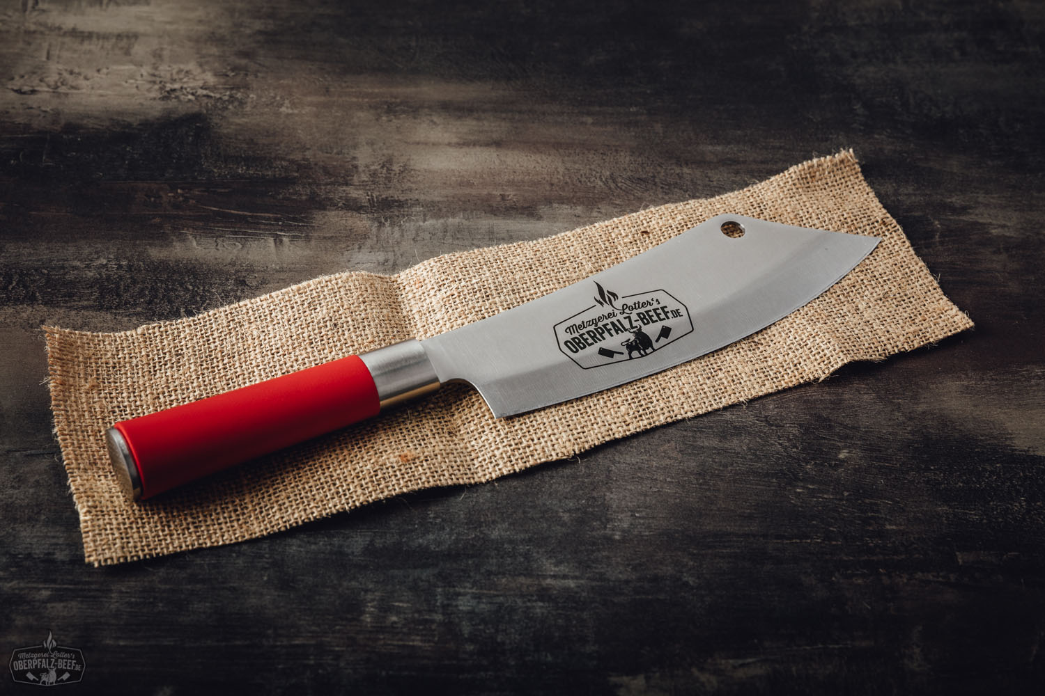 Koch- und Grillmesser Dick Ajax Red Spirit mit breiter Klinge und rotem Griff, liegend auf schwarzem Hintergrund – hochwertiges Küchenmesser für Fleisch, Grill und BBQ.