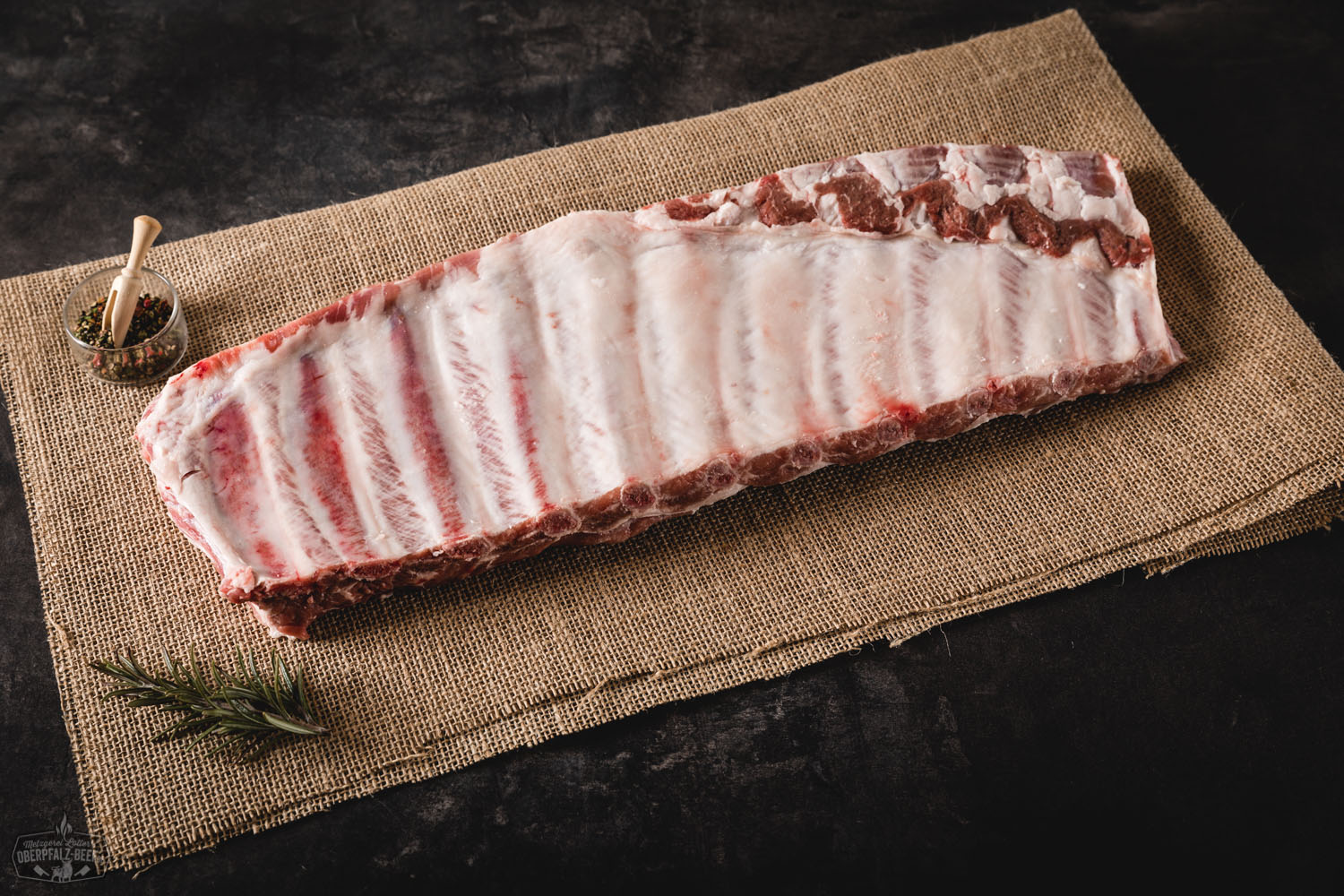 Spare Ribs St. Louis Style vom Oberpfälzer Landschwein – tiefgekühlt in Premium-Qualität Spare Ribs St. Louis Style vom Oberpfälzer Landschwein, saftig gegrillt mit karamellisierter BBQ-Marinade, angerichtet auf rustikalem Holzbrett mit Kräutergarnitur und Grillzange im Hintergrund.