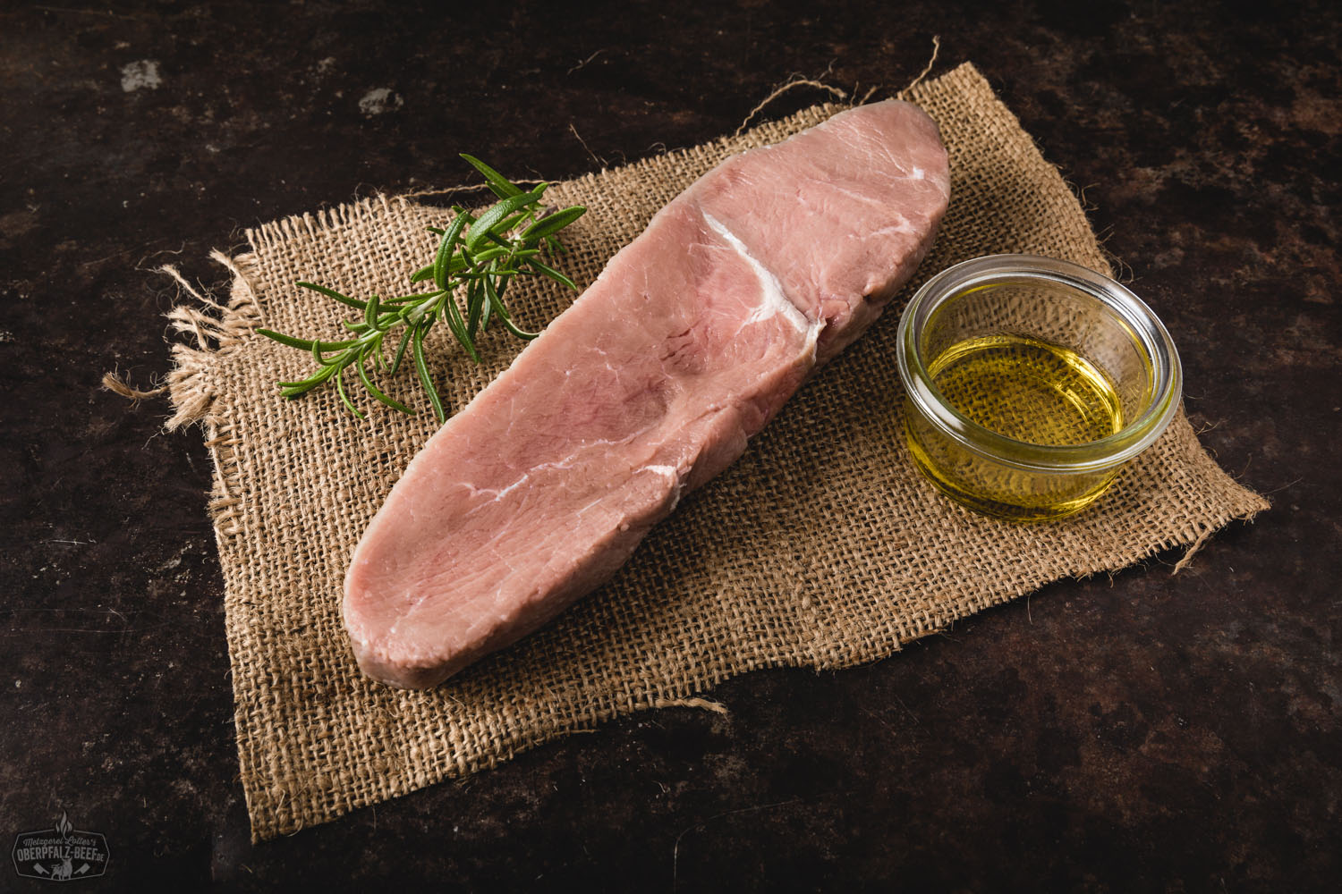 Zartes Kalbshüftsteak frisch gegrillt auf Holzbrett serviert Kalbs-Huftsteak roh auf dunklem Holzbrett angerichtet, mit grobem Meersalz bestreut, frischen Rosmarinzweigen und Knoblauch dekoriert – hochwertiges Fleisch, ideal zum Grillen oder Braten.