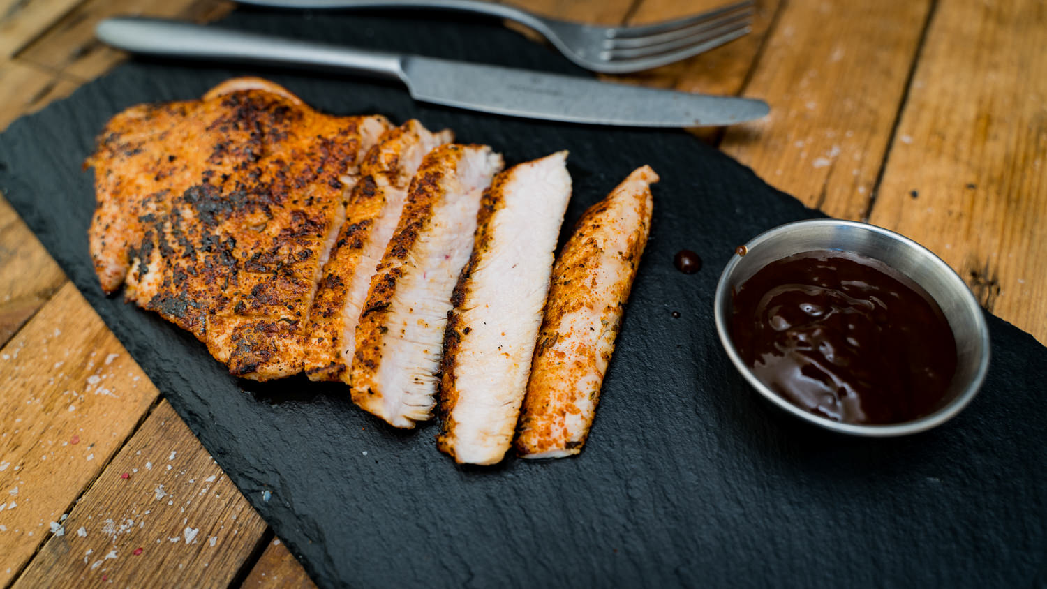 Gewürzte Putensteaks – Frisches Geflügelfleisch für den Grill oder die Pfanne Drei gewürzte Putensteaks roh auf einem dunklen Holzbrett angerichtet, dekoriert mit grobem Pfeffer, Rosmarinzweigen, Chili, Salzflocken und Knoblauch – hochwertiges Frischfleisch für Grill oder Pfanne.