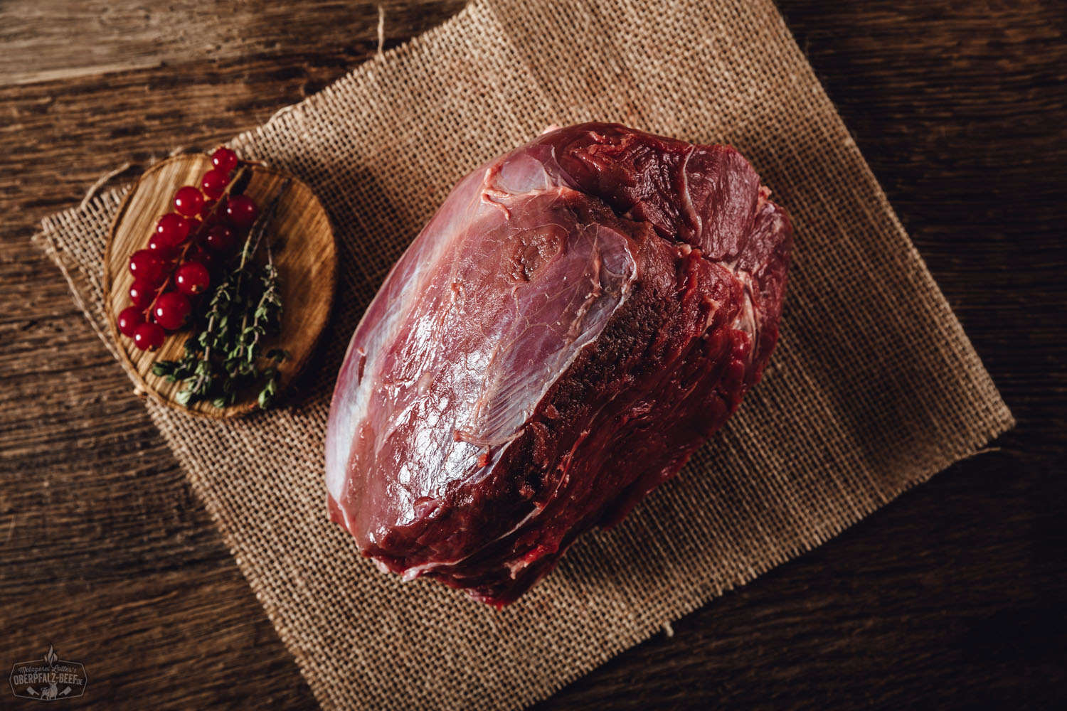 Rohes, mageres Stück Hirschfleisch (Nuss) aus der Oberpfalz, saftig rot mit feiner Marmorierung, auf dunklem Untergrund liebevoll angerichtet – hochwertiges Wildfleisch vom Oberpfälzer Hirsch, ideal für Braten oder Steaks.