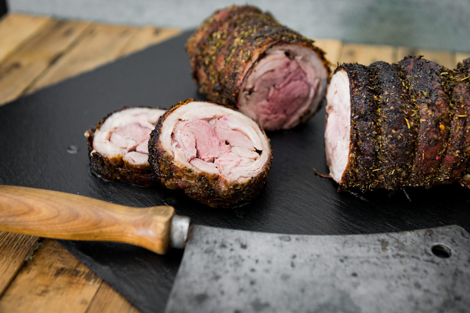 Magerer Lammrollbraten vom Juradistl-Lamm – hochwertiges Fleisch aus der Oberpfalz Saftiger Lammrollbraten, mager und goldbraun gebraten, aufgeschnitten und dekorativ angerichtet auf rustikalem Holzbrett mit Kräutergarnitur – hochwertiges Fleisch vom Juradistl-Lamm.