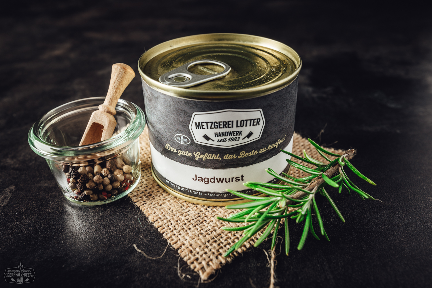 Frische grobe Leberwurst in Naturdarm, angeschnitten auf Holzbrett mit Schnittfläche sichtbar, daneben Gewürze wie Pfefferkörner und Kräuter; rustikale Präsentation, ideal für regionale Spezialitäten, Metzgerei-Qualität und bayerischen Brotzeitgenuss.