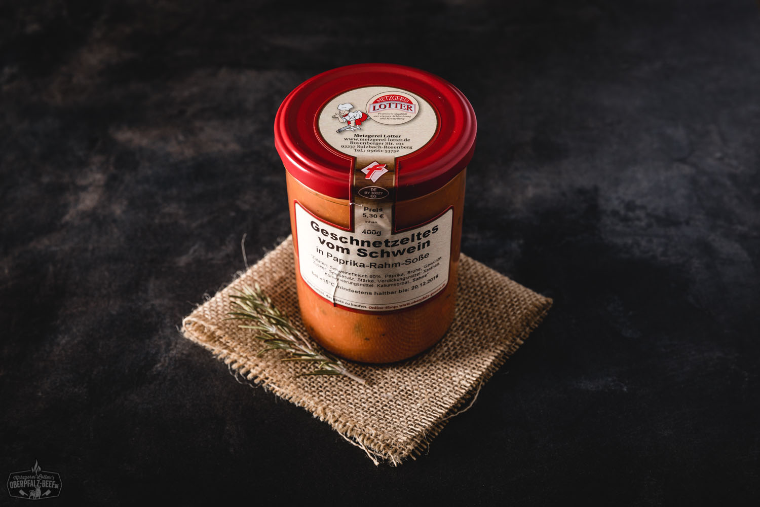 Schweinegeschnetzeltes in Paprika-Rahm-Soße im Glas – Hausgemacht & Fertiggericht Schweinegeschnetzeltes in cremiger Paprika-Rahm-Soße, servierfertig im Glas mit sichtbaren Paprikastücken und zartem Fleisch, auf hellem Untergrund präsentiert – hochwertige Hausmannskost im Glas.