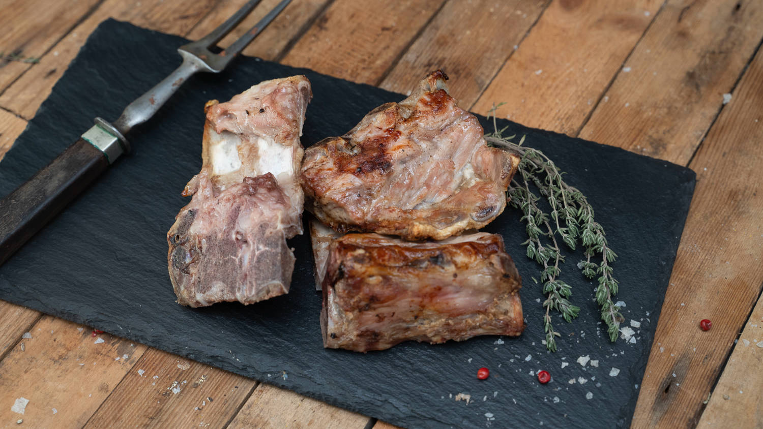 Schweinefleisch vom Oberpfälzer Landschwein – Regional, Frisch & Nachhaltig Rohes Schweinefleisch vom Oberpfälzer Landschwein, in frischen, saftigen Stücken auf einem dunklen Untergrund präsentiert, umgeben von Gewürzen wie Rosmarin, Knoblauch und Pfefferkörnern – hochwertiges regionales Fleisch für bewussten Fleischgenuss.