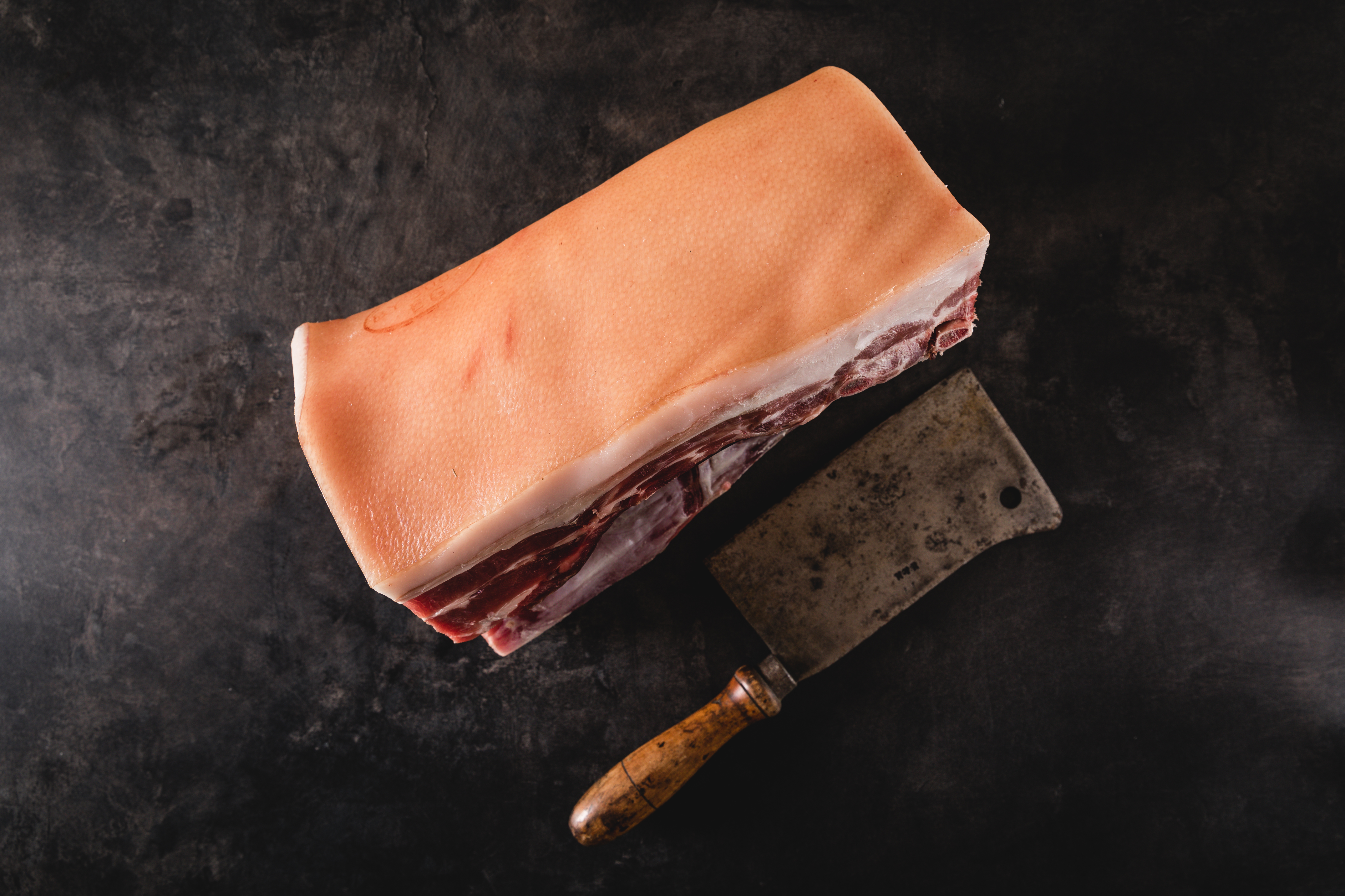 Landschwein Fleischqualität Oberpfalz Beef Premium Schweinefleisch Bild eines geräucherten Landschweinbratens aufgeschnitten auf einem Holzbrett mit frischen Kräutern, Tomaten und Knoblauch. Perfekt für traditionelle bayerische Küche und Grillrezepte.