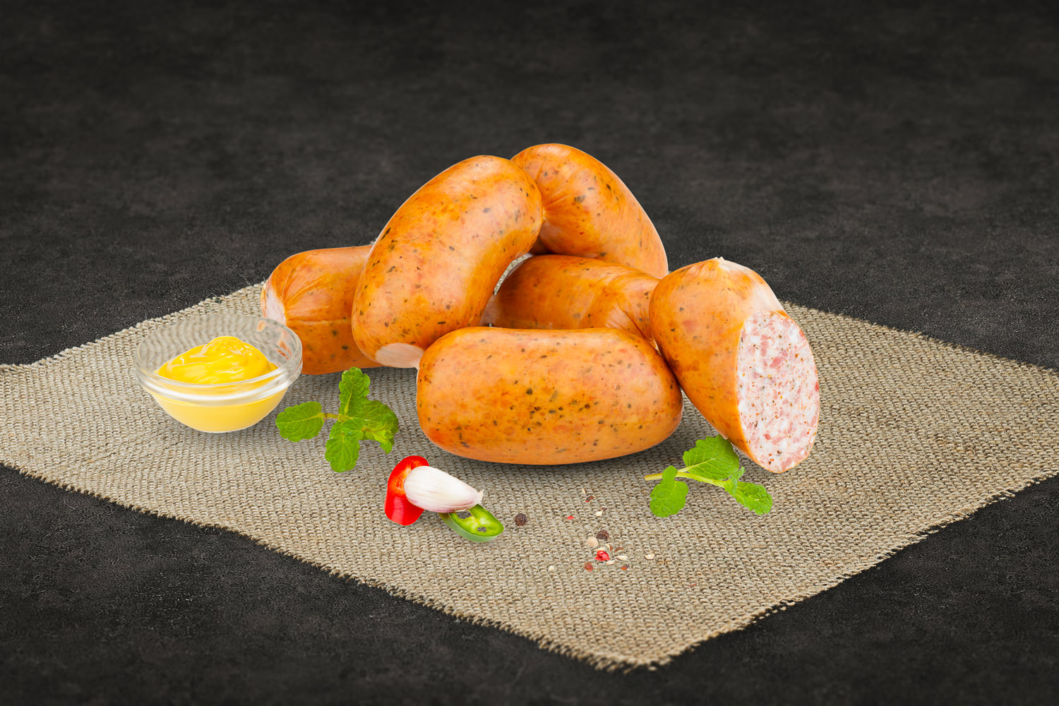 Aufgeschnittene Puten-Jagdwurst auf Holzbrett, fein marmoriert mit sichtbaren Gewürzstücken, daneben frische Kräuter und Pfefferkörner – hochwertige Geflügelwurst aus der Region Oberpfalz.