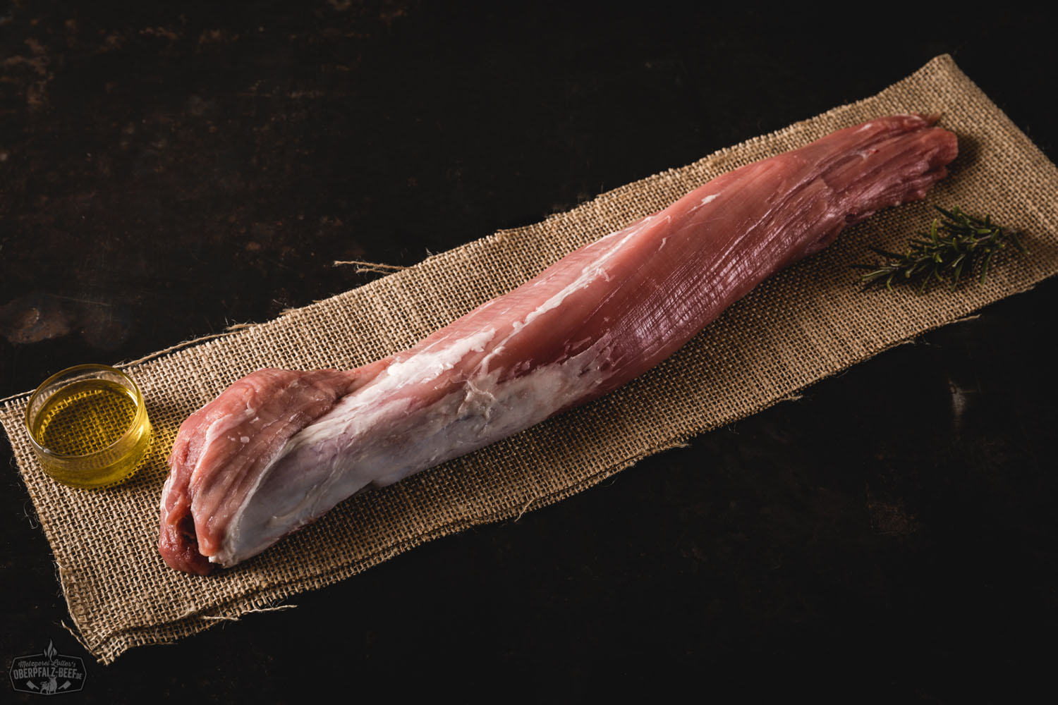 Frisch gebratenes Filet vom Oberpfälzer Milchkalb auf einem Holzbrett angerichtet, serviert mit Rosmarinzweigen, grobem Meersalz und buntem Pfeffer – hochwertiges Kalbfleisch für Feinschmecker.