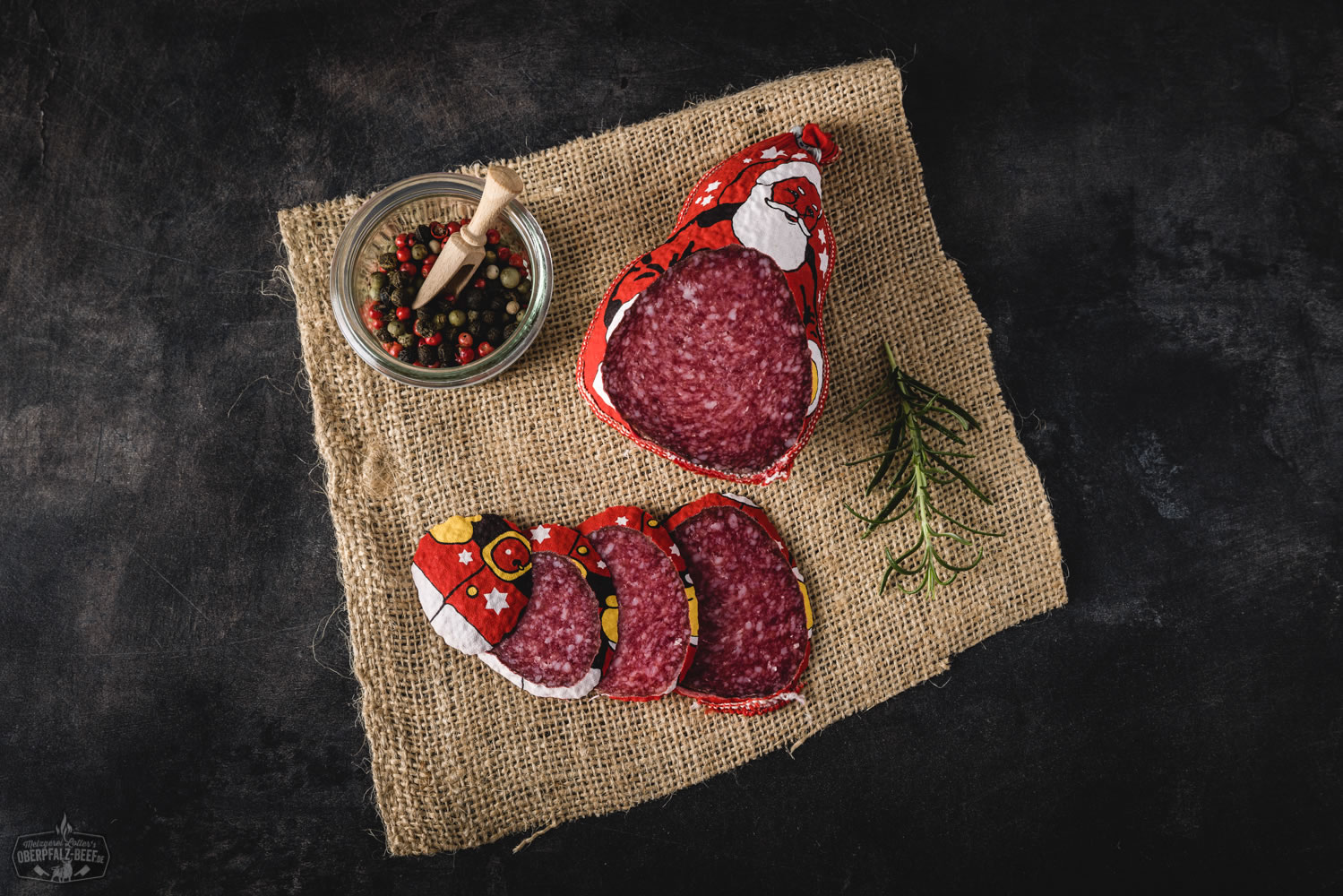 Weihnachtssalami in Nikolausform – Festliche Spezialität aus der Oberpfalz Weihnachtssalami in Form eines Nikolaus mit festlicher Verpackung, rotem Hintergrund und Weihnachtsdekoration. Ideal für Geschenke zur Weihnachtszeit.