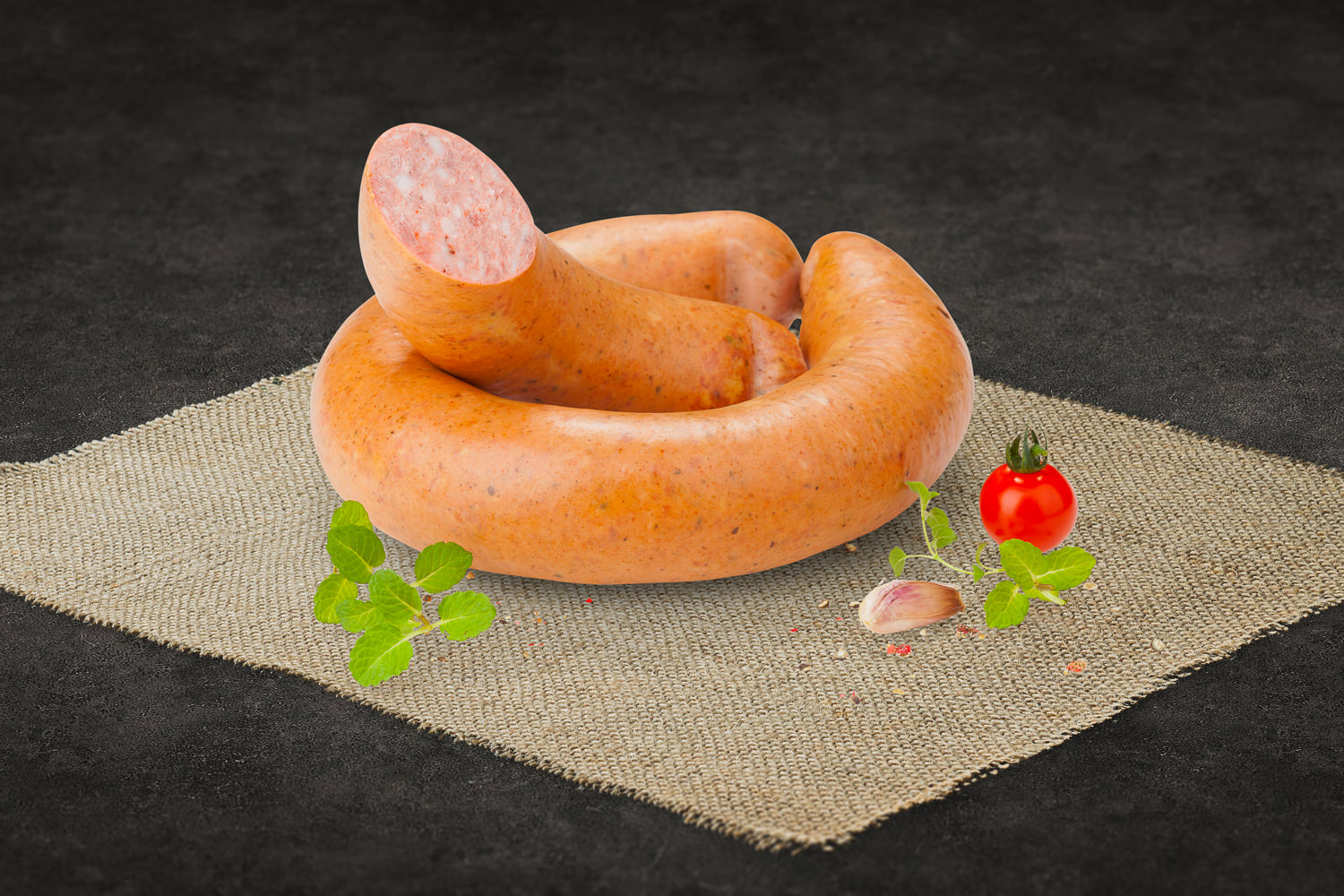 Aufgeschnittener Rosmarinschinken auf einem hellen Holzbrett, dekoriert mit frischem Rosmarin und Pfefferkörnern; zartrosa Fleisch mit feiner Marmorierung, appetitlich angerichtet für Feinkost oder Brotzeit.