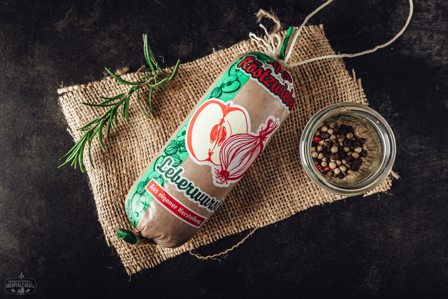 Apfel-Zwiebel-Kalbsleberwurst als Portion – Hausmacher Wurst im Naturdarm Gegrillter Kräuterkäse auf schwarzem Untergrund, rechteckiger Käse mit goldbrauner Kruste, bestreut mit grünen Kräutern, serviert auf Brett mit Beilagen wie Rosmarinzweig und Gewürzen – deftiger vegetarischer Grillgenuss aus der Oberpfalz.