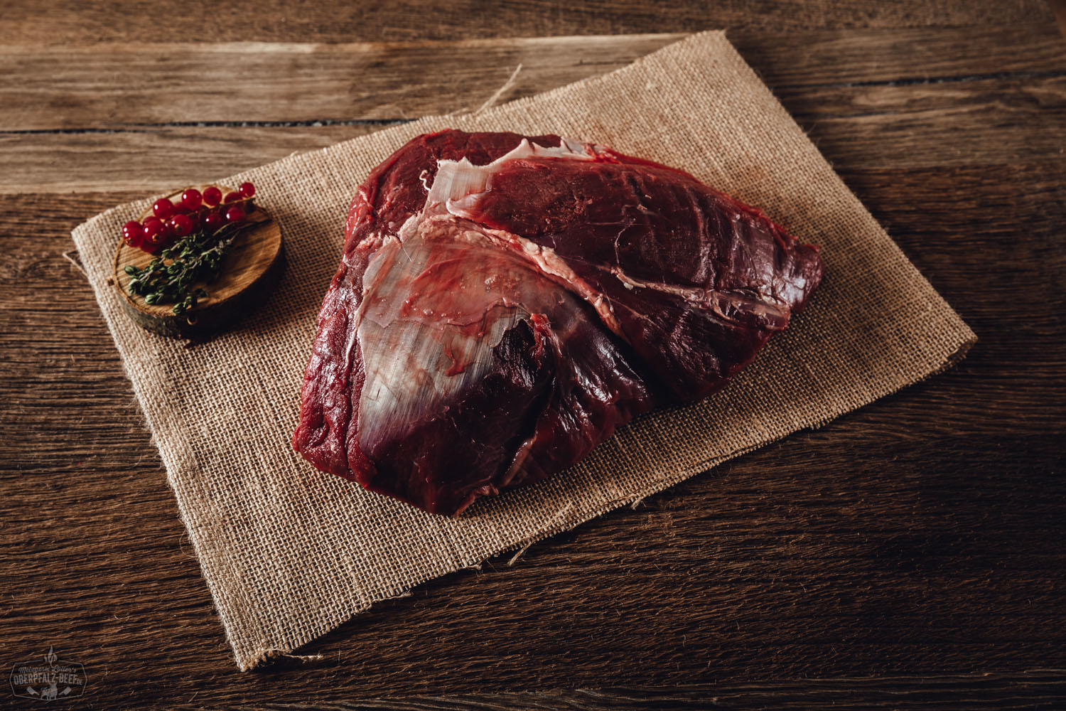 Halbe Schulter mit Knochen vom Oberpfälzer Hirsch – Wildfleisch Premiumqualität Rohe, halbe Schulter mit Knochen vom Oberpfälzer Hirsch auf dunklem Untergrund, frisch zugeschnitten, kräftig marmoriert, mit sichtbarem Schulterblatt – hochwertiges Wildfleisch aus regionaler Jagd, ideal für Braten oder Schmorgerichte.