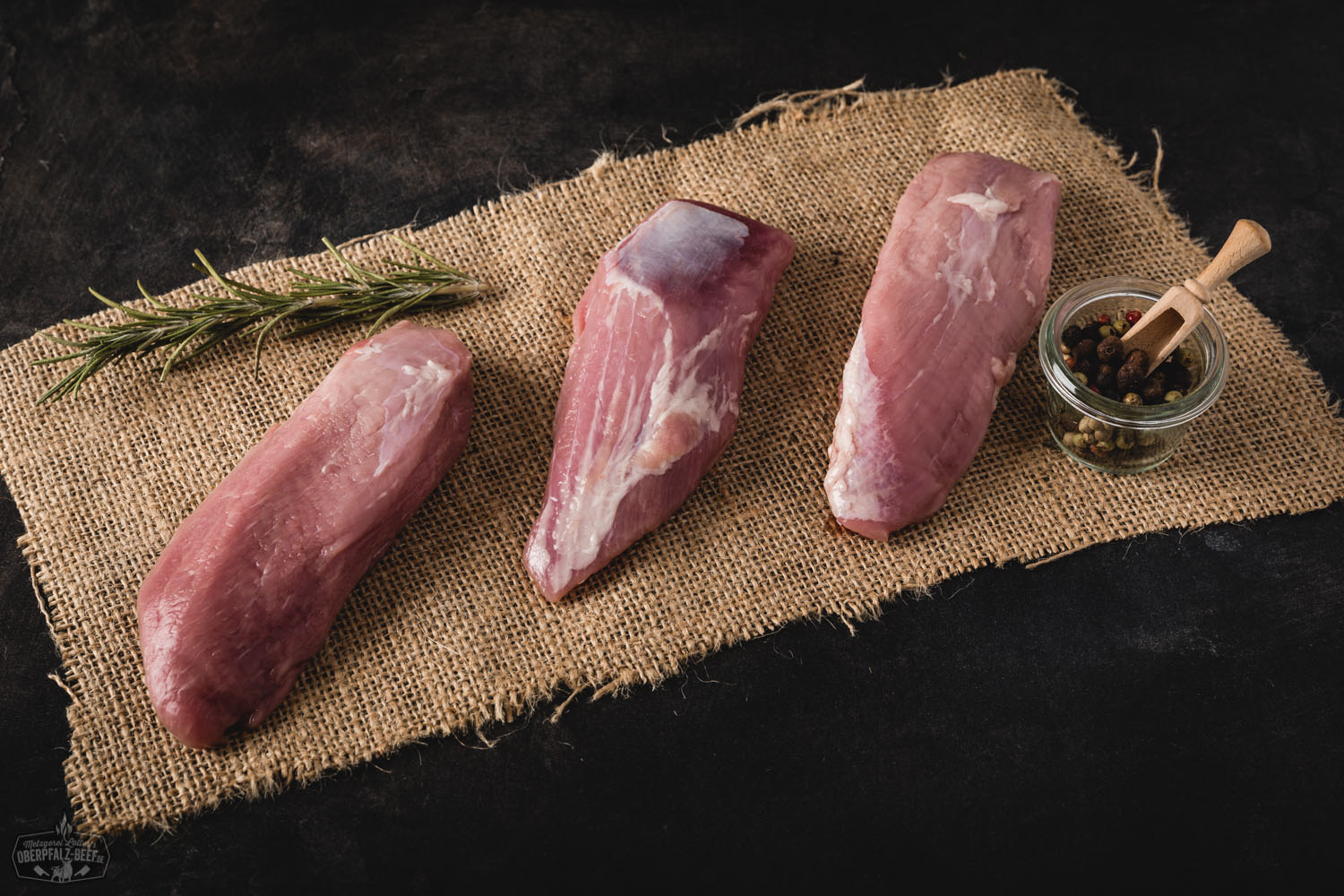 Nahaufnahme eines perfekt gegarten Teres Major Cuts vom Oberpfälzer Landschwein auf dunklem Untergrund, saftig rosa im Inneren mit kräftiger Kruste, daneben grobes Meersalz und frische Kräuter – hochwertiges Fleischprodukt für bewusste Genießer.