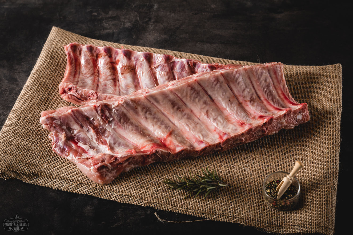 Tiefgefrorene Baby Back Ribs vom Schwein auf weißem Untergrund Tiefgefrorene Baby Back Ribs vom Schwein, roh und portionsweise vakuumverpackt, auf schwarzem Untergrund mit sichtbaren Eispartikeln – hochwertige Fleischqualität für BBQ und Grillgerichte.
