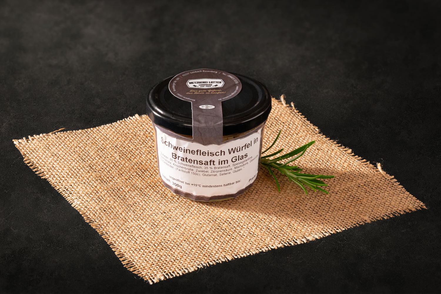 Nahaufnahme von zarten Schweinefleischwürfeln in dunklem Bratensaft, angerichtet in einer gusseisernen Pfanne auf rustikalem Holzuntergrund – deftiges Schmorfleischgericht, traditionell bayerisch zubereitet.