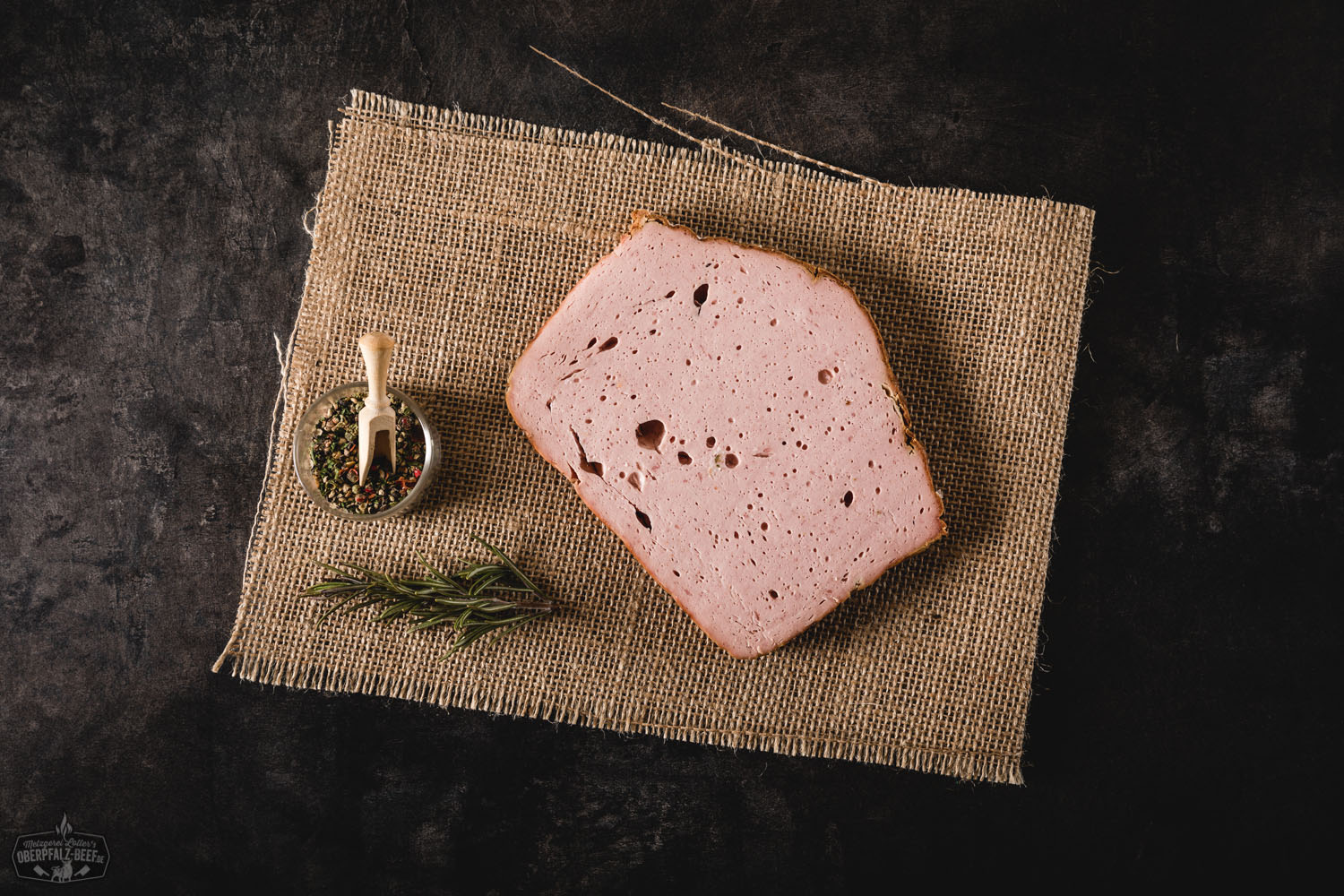 Leberkäsescheibe auf Holzbrett mit Senf – Bayerische Brotzeit Frisch aufgeschnittene Brotzeitscheibe Leberkäse auf dunklem Holzbrett, umgeben von rustikalem Bauernbrot, eingelegten Gurken und Senf – herzhafte bayerische Spezialität als deftiger Imbiss angerichtet.