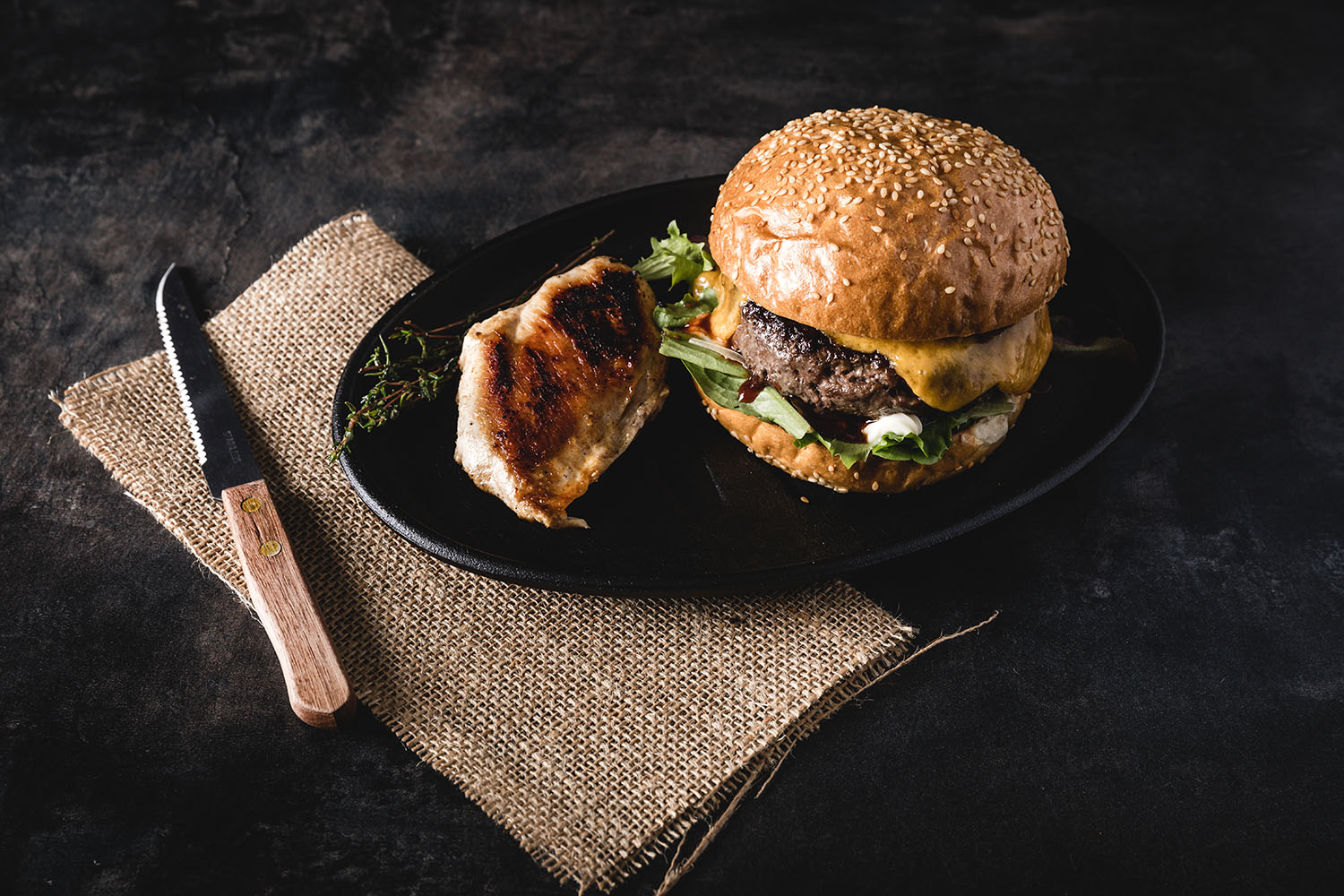 Wild-Burger-Paket mit Mini-Patties aus regionalem Wildfleisch – Premiumqualität für Grill & Küche Vier roh geformte Wild-Mini-Burger-Patties liegen auf dunklem Untergrund, umgeben von Zutaten wie roten Zwiebeln, Rosmarinzweigen, Pfefferkörnern und Wacholderbeeren – hochwertiges Wildfleisch für Burger, frisch und regional präsentiert.