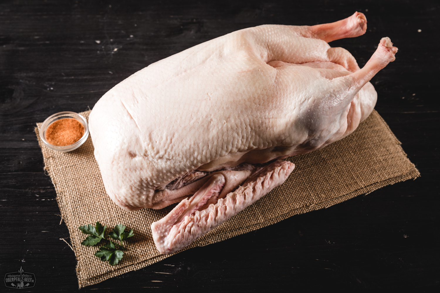 Halbe, knusprig gebratene Oberpfälzer Weihnachtsgans auf dunklem Teller angerichtet, umgeben von Bratensoße, Apfelrotkohl und Kartoffelknödeln, serviert auf rustikalem Holztisch – traditionelles deutsches Weihnachtsessen.