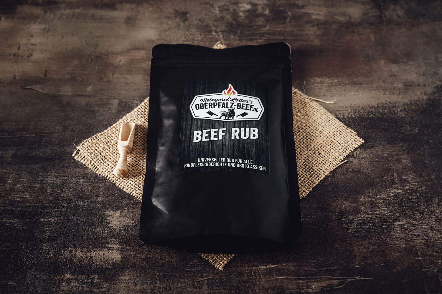 Glas mit Gewürzmischung „Oberpfalz Beef Rub“ auf dunklem Untergrund, daneben grobes Salz, schwarze Pfefferkörner, Chilischoten und Knoblauch – ideal zum Würzen von Grillfleisch und BBQ.