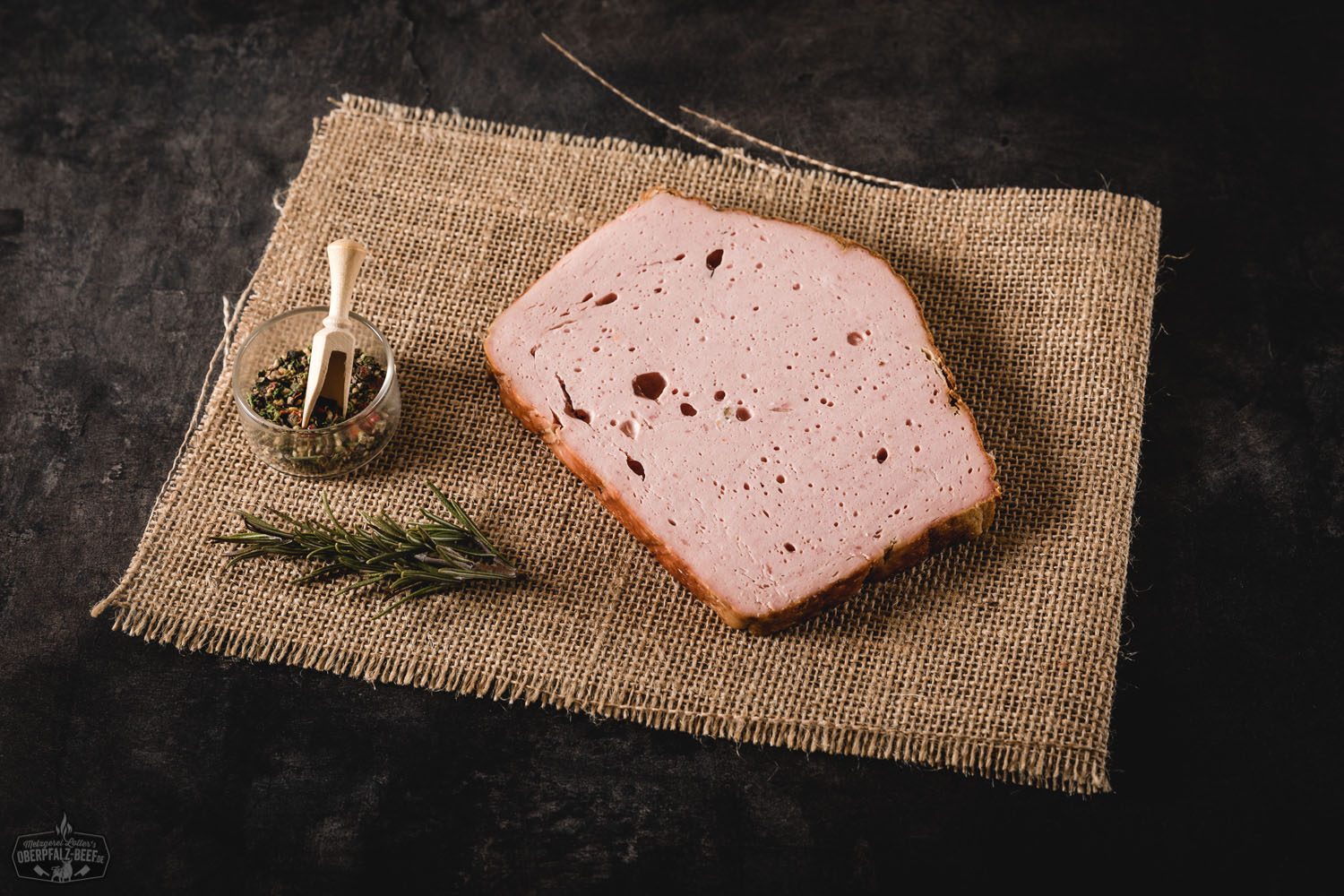 Leberkäsescheibe auf Holzbrett mit Senf – Bayerische Brotzeit Frisch aufgeschnittene Brotzeitscheibe Leberkäse auf dunklem Holzbrett, umgeben von rustikalem Bauernbrot, eingelegten Gurken und Senf – herzhafte bayerische Spezialität als deftiger Imbiss angerichtet.