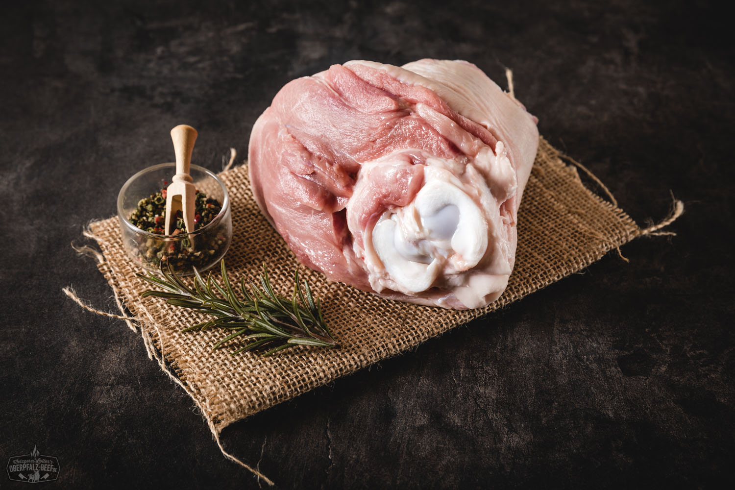 Knusprig gebratene Spanferkel-Hinterhaxen vom Oberpfälzer Landschwein auf einem Holzbrett angerichtet, mit krosser Kruste und saftigem Fleisch, serviert als traditionelle bayerische Delikatesse in rustikalem Umfeld.