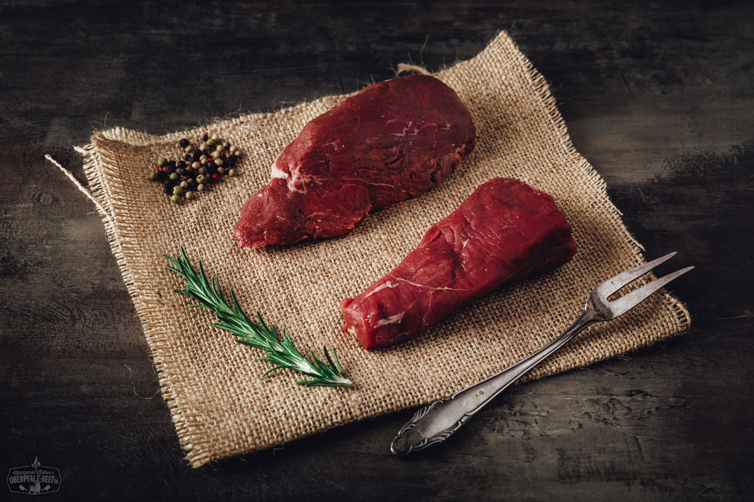 Rohe Filetspitzen vom Oberpfalz-Rind auf schwarzem Schneidebrett, marmoriert und Wet Aged gereift, mit Rosmarinzweig und grobem Salz garniert – hochwertiges Rindfleisch für Steak oder Feinschmeckergerichte.